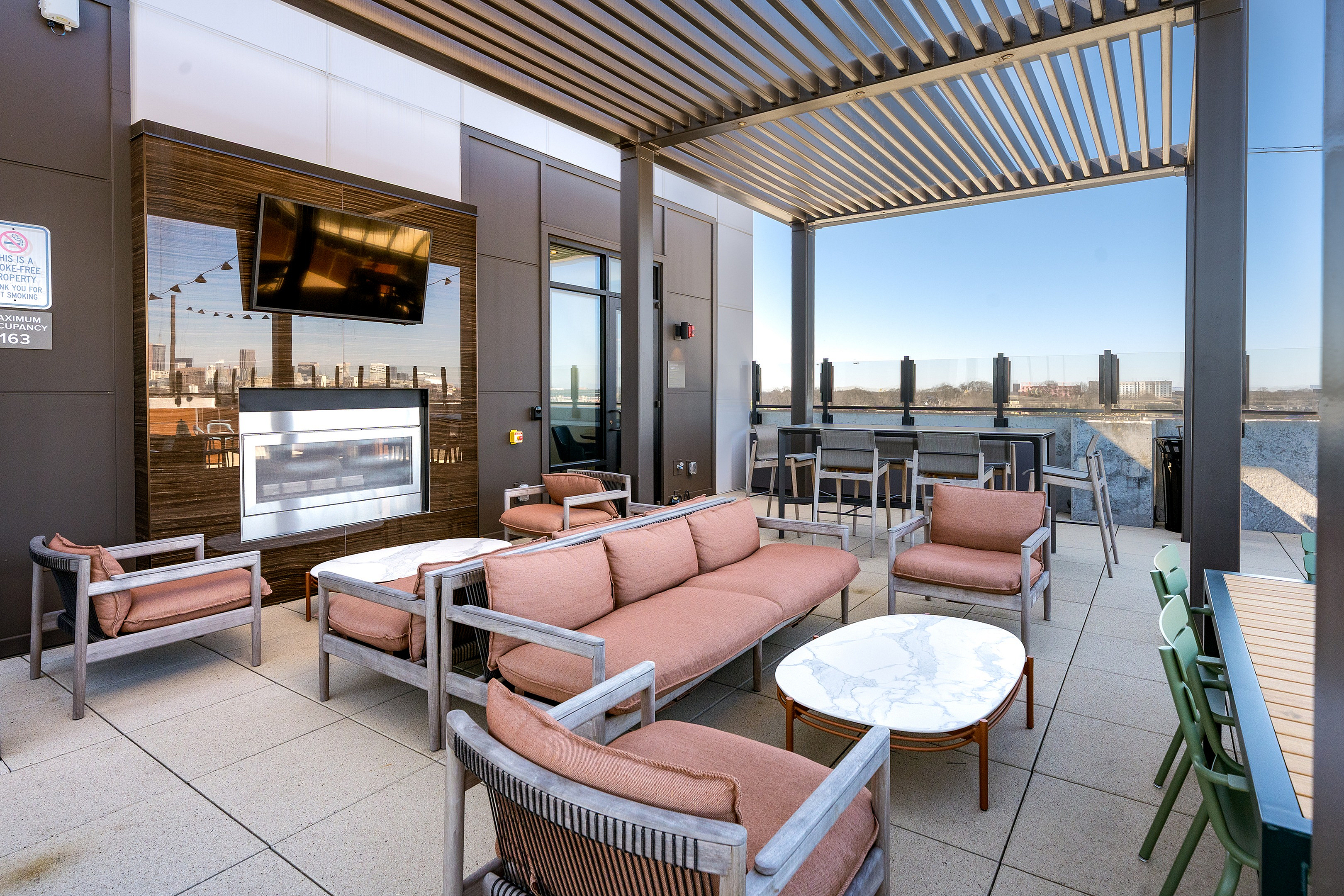 Chic rooftop lounge with modern seating, a flat-screen TV, and panoramic city views, perfect for entertaining.