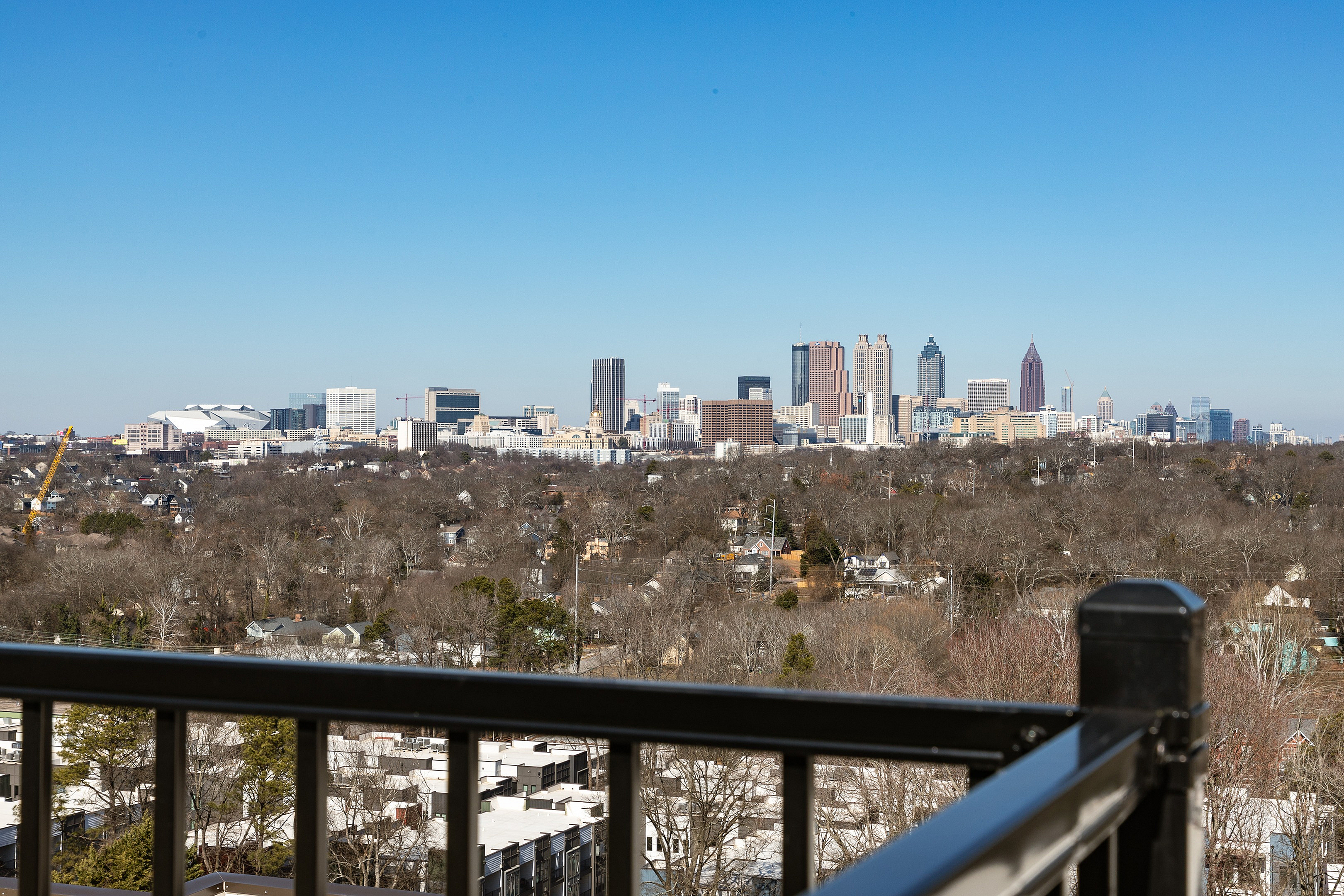 Breathtaking city skyline view from a balcony, showcasing vibrant urban landscape and clear blue skies.