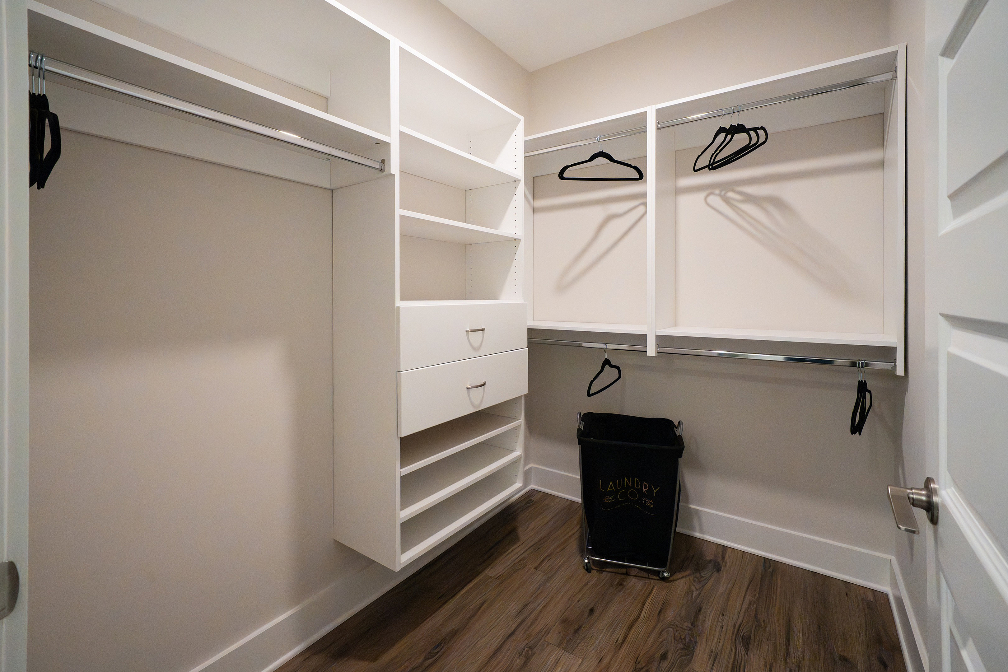 Spacious walk-in closet with modern shelving, hanging rails, and sleek hardwood flooring, perfect for all your storage needs.