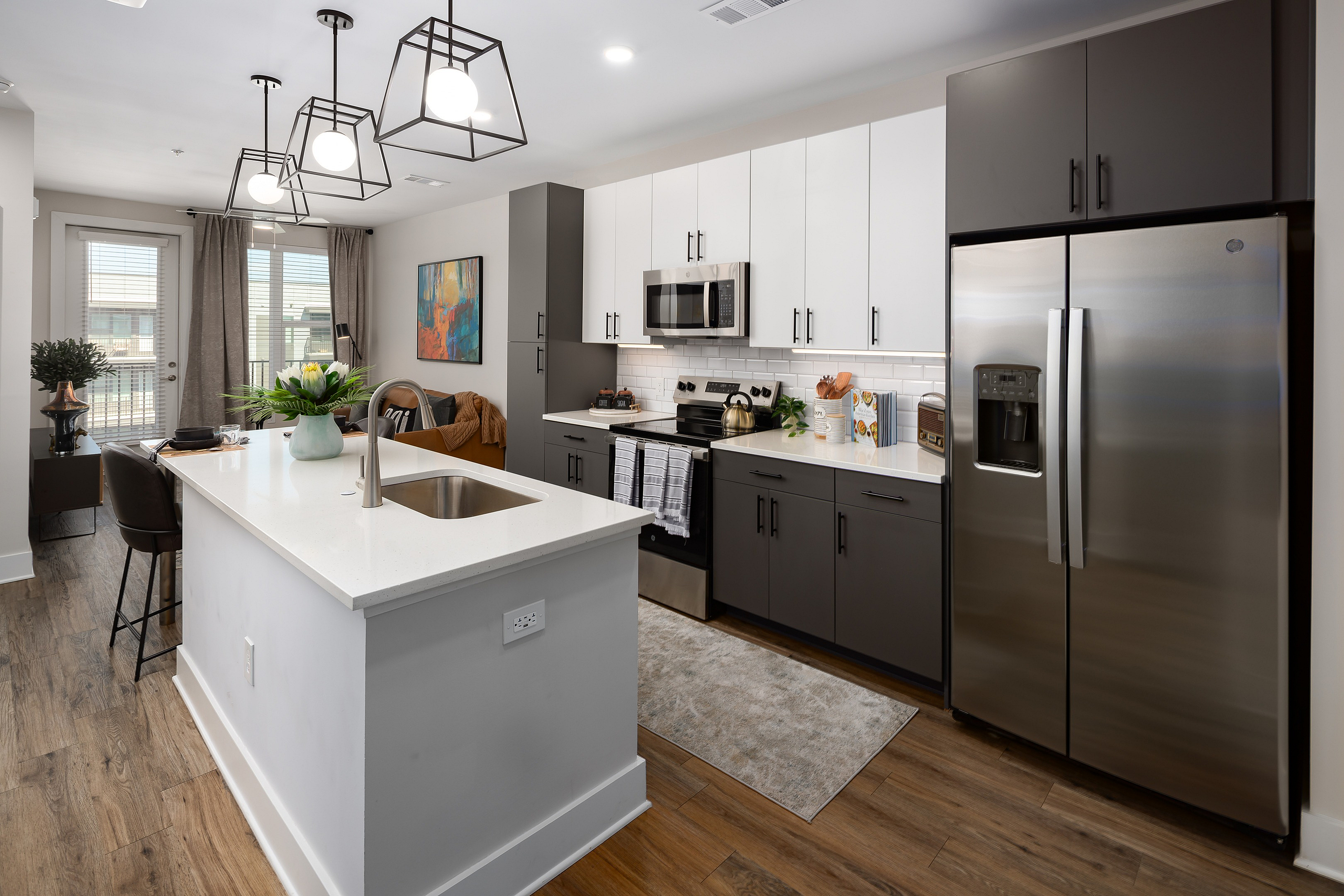 Modern kitchen featuring sleek white and dark cabinetry, stainless steel appliances, and an inviting island with pendant lighting.