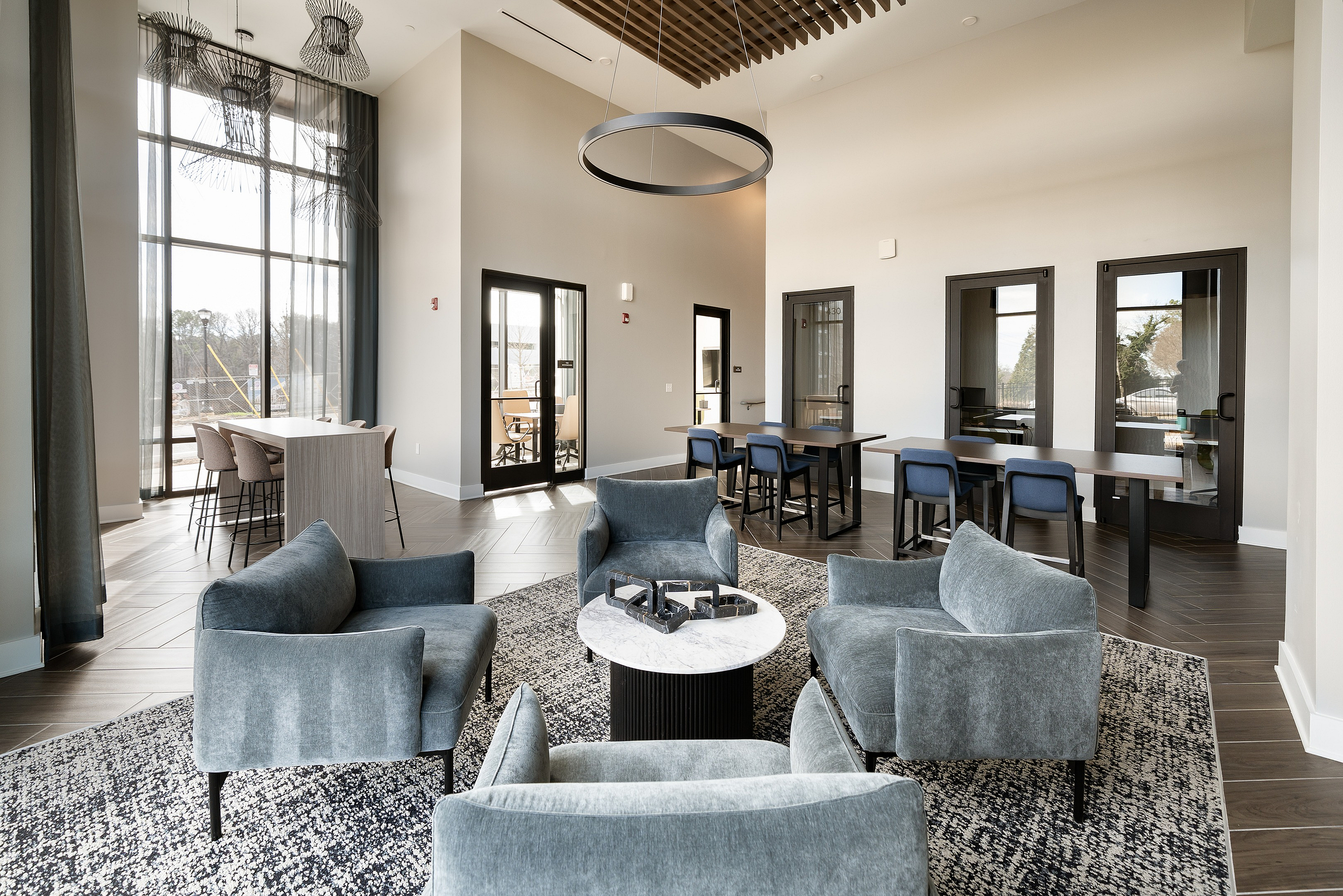 Elegant and modern communal lounge area with plush seating, sleek conference tables, and floor-to-ceiling windows offering natural light.