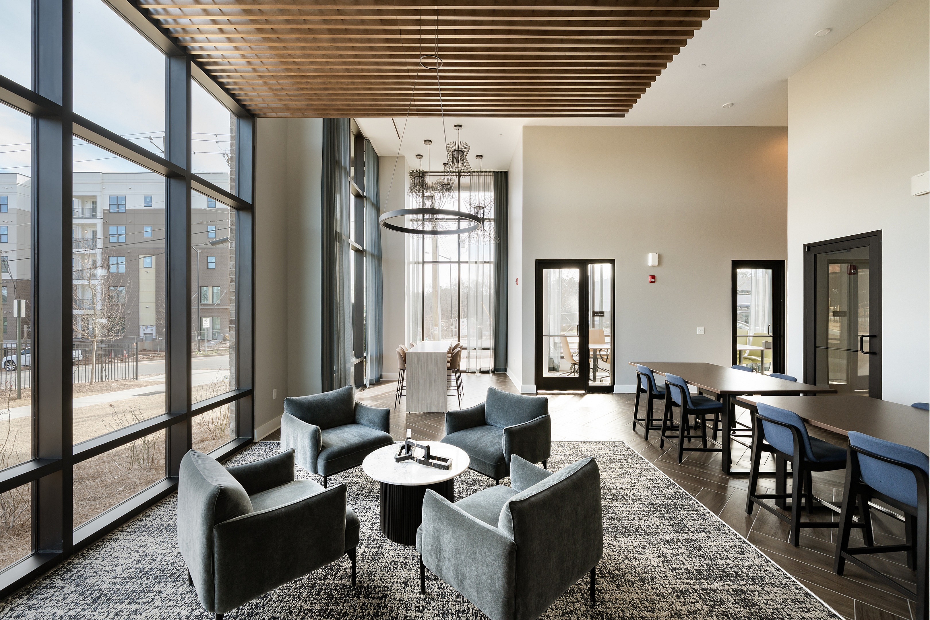 Bright and modern apartment lounge with chic seating, large windows, and a sophisticated dining area, perfect for relaxation and gatherings.