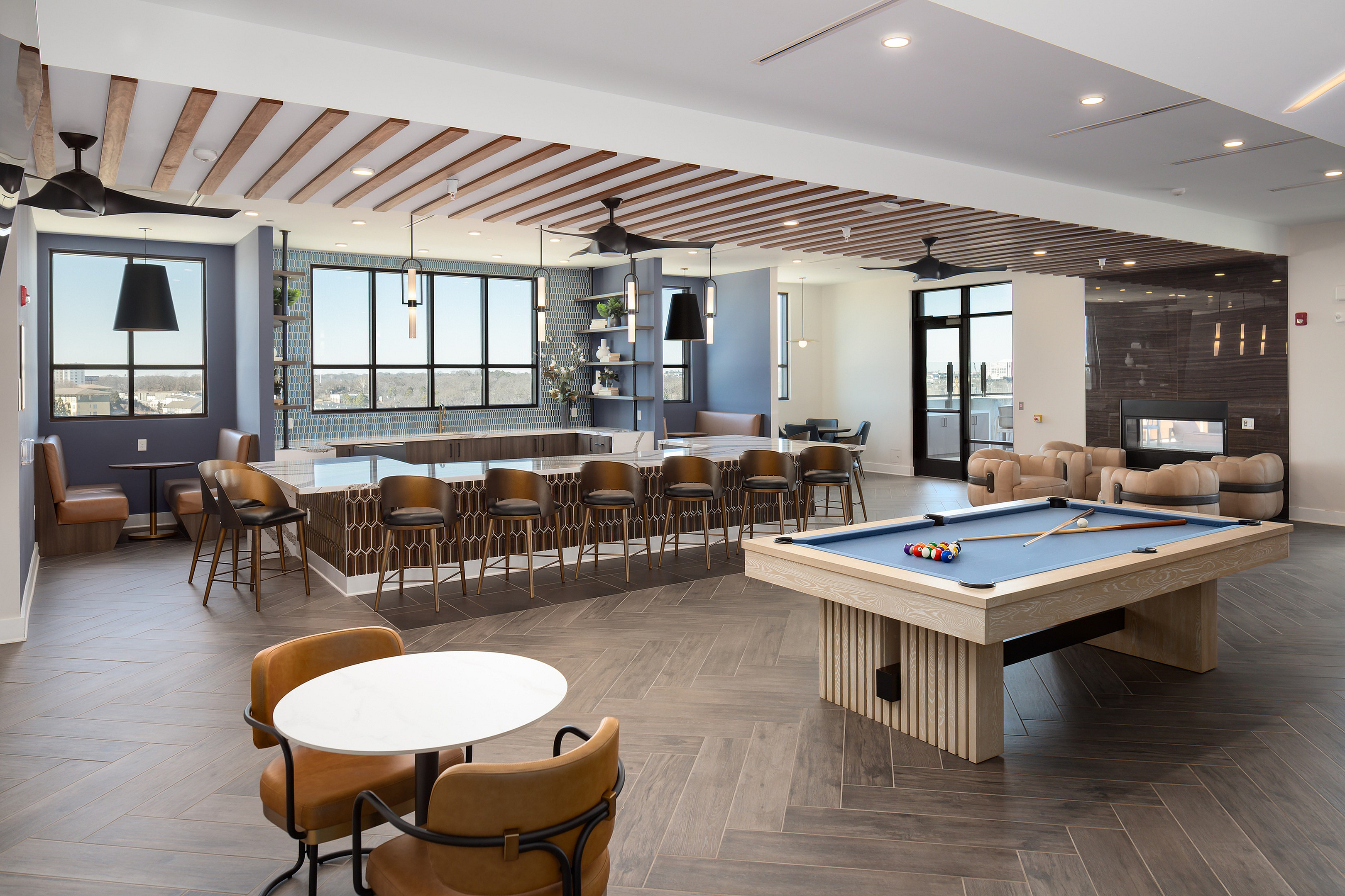 Luxurious open-concept entertainment room featuring a modern kitchen with bar seating, stylish lounge area, and billiards table, perfect for social gatherings.