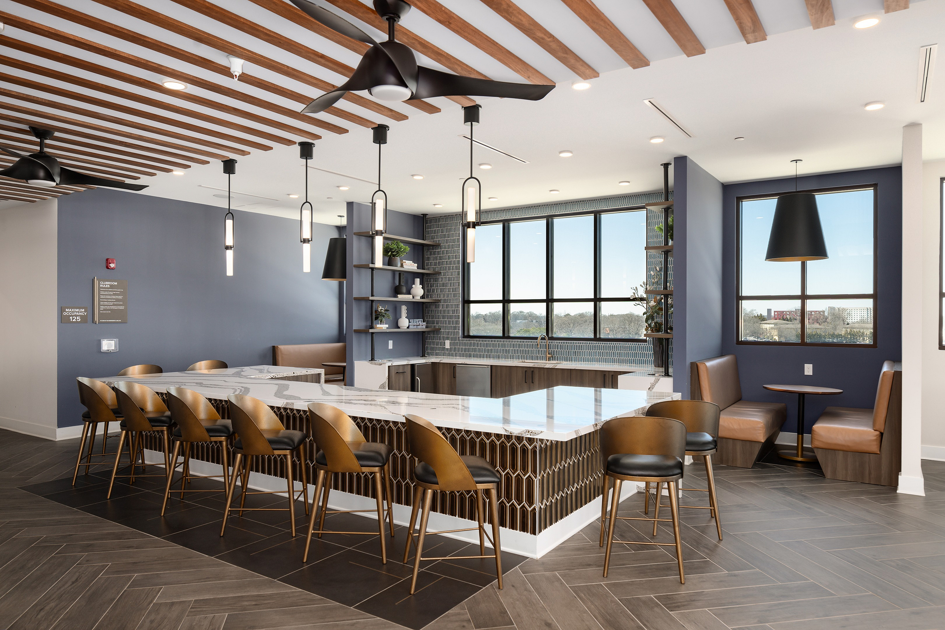 Sophisticated communal kitchen with chic bar seating, modern pendant lights, and a panoramic window view.