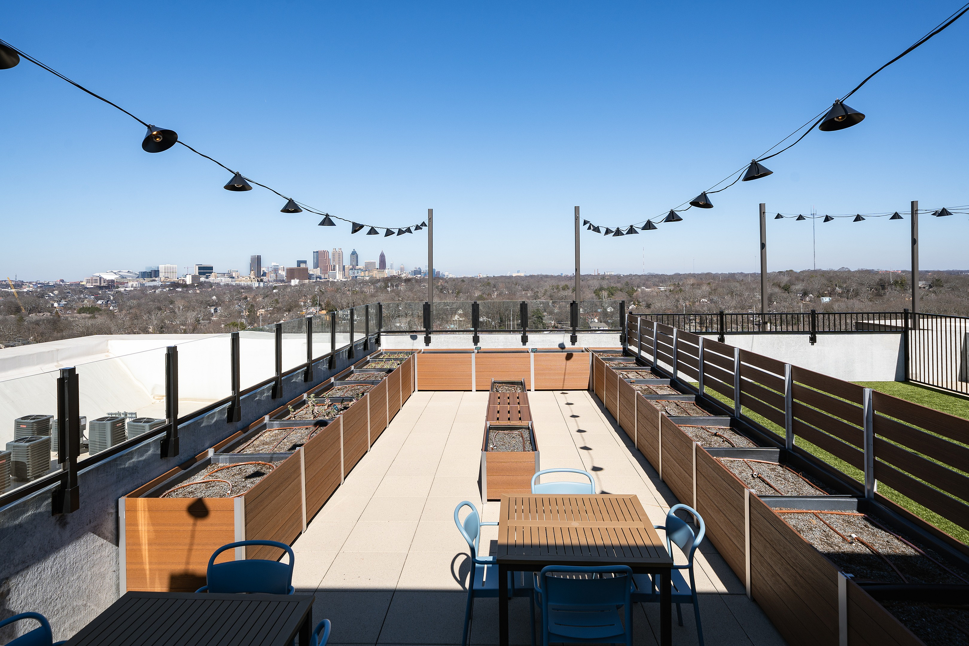Stunning rooftop terrace with modern seating, planter boxes, and a breathtaking city skyline view.