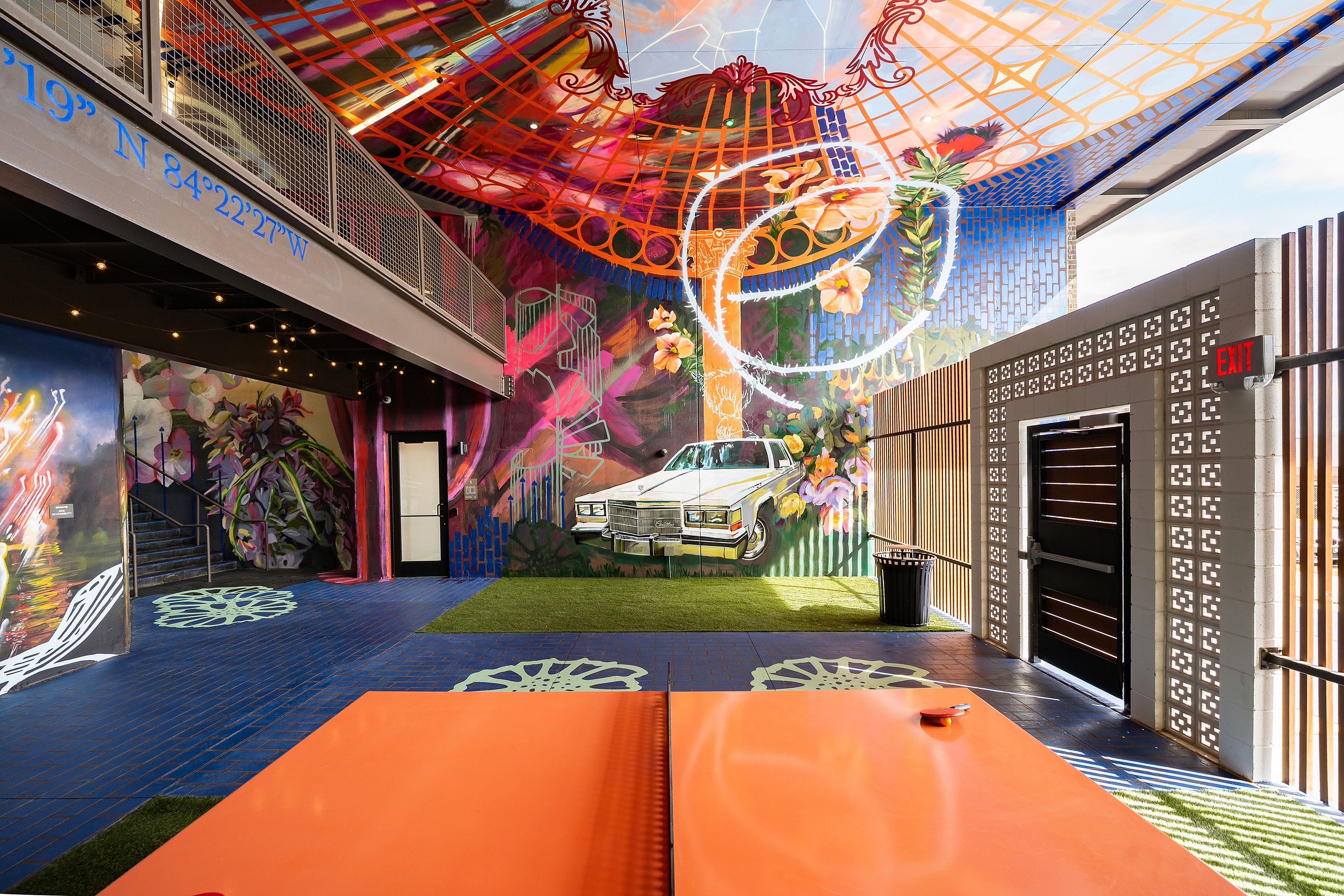 Vibrant urban space with colorful graffiti murals, featuring a classic car and lush greenery, ideal for creative inspiration.