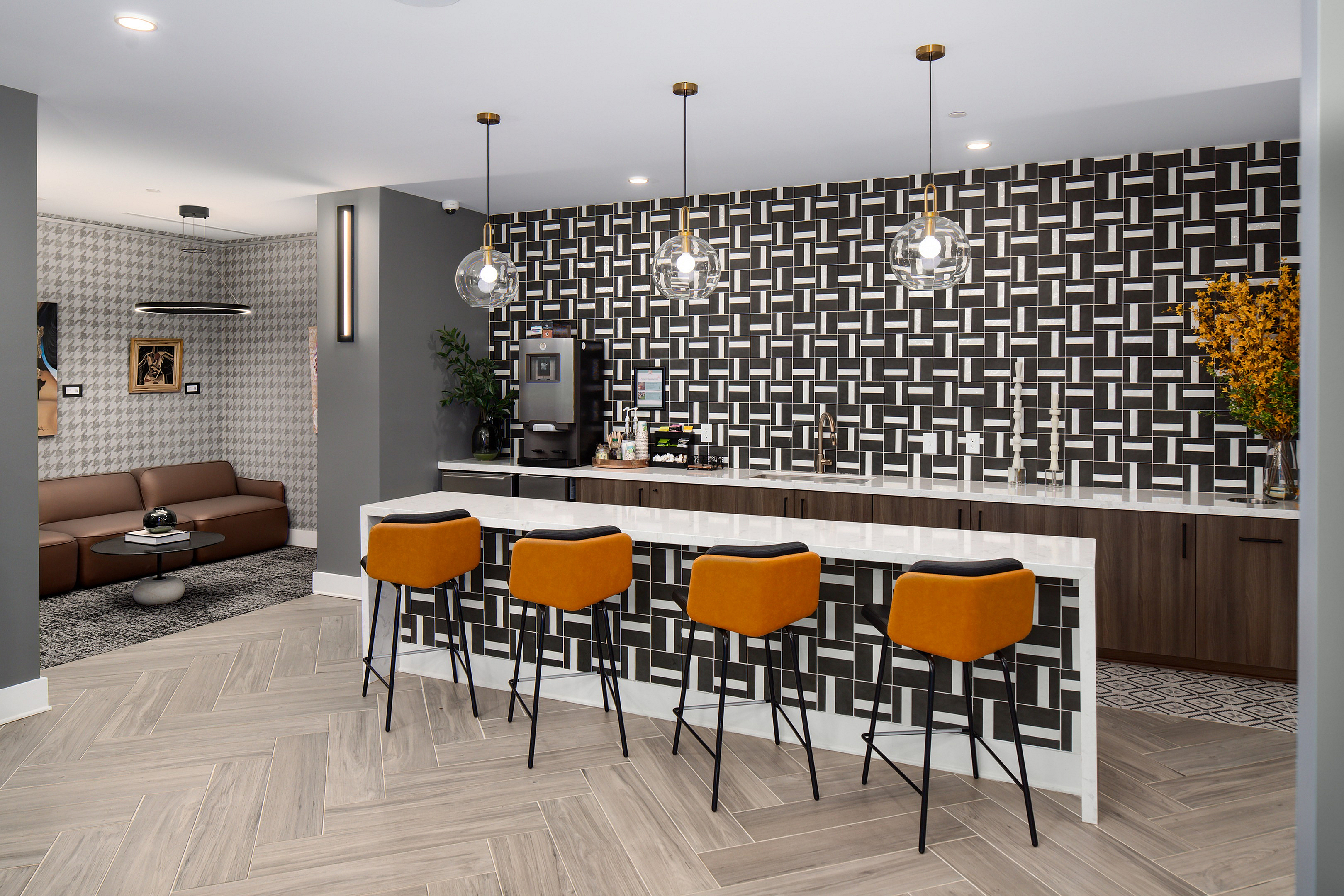 Chic apartment lounge with stylish bar seating, modern lighting, and a bold geometric backsplash.