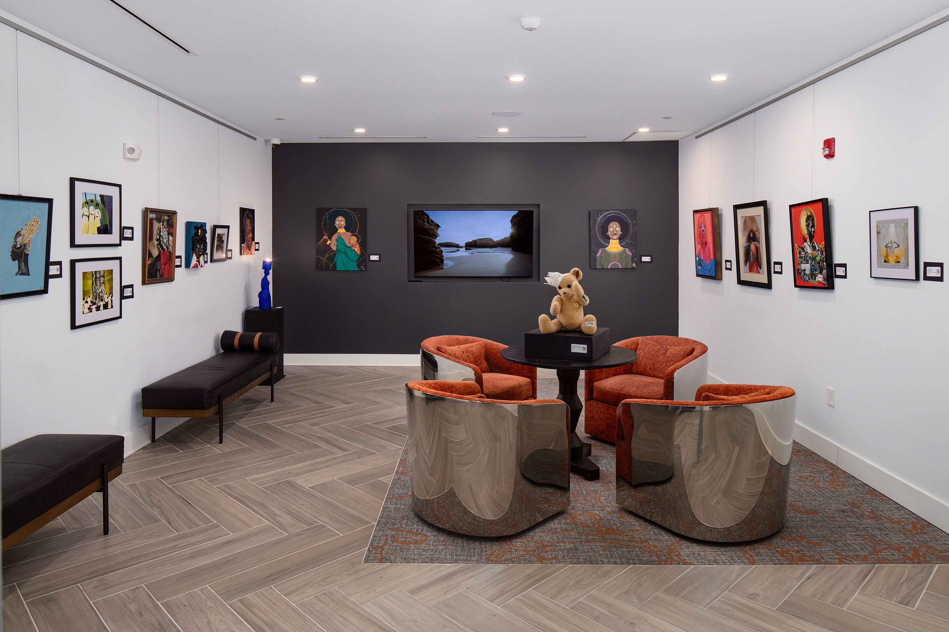 Contemporary art gallery lounge featuring vibrant artwork, cozy seating with plush chairs, and elegant wood flooring.