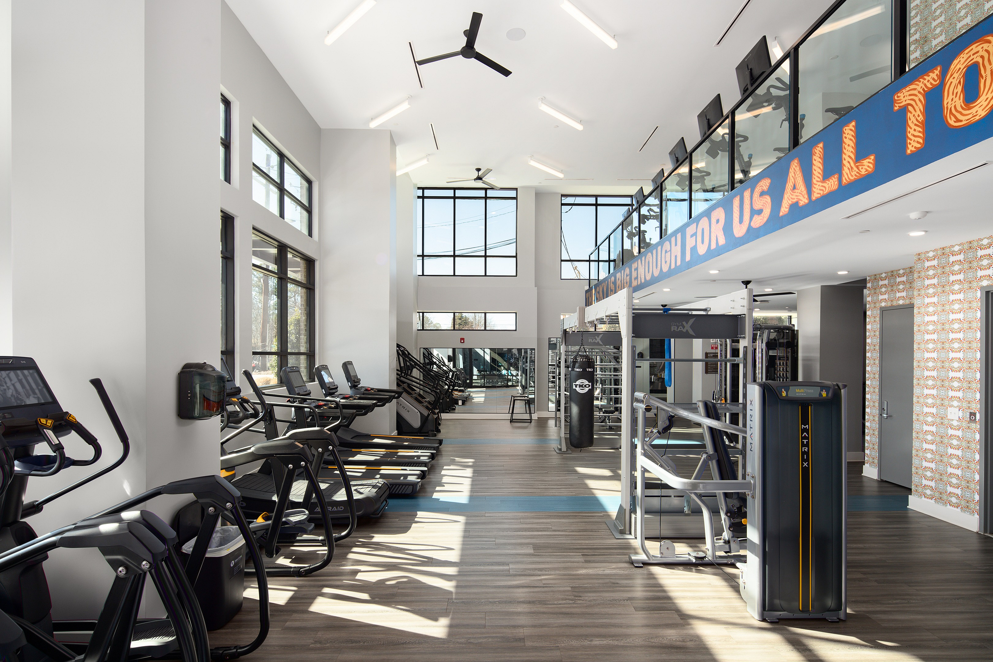 Bright and modern fitness center with state-of-the-art equipment, high ceilings, and large windows for natural light.