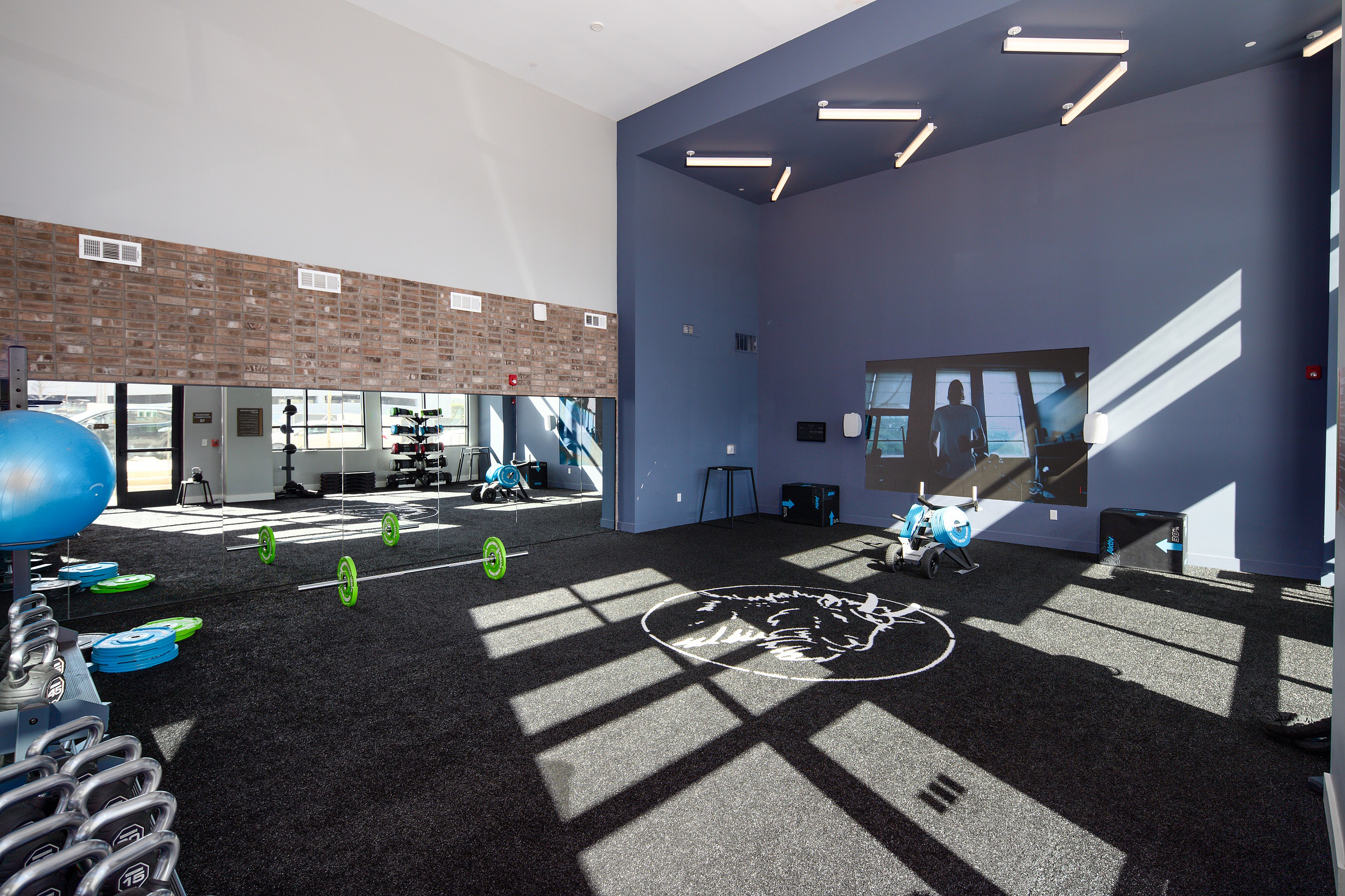Bright, spacious gym with modern equipment, mirrored walls, and industrial accents, perfect for energetic workouts.