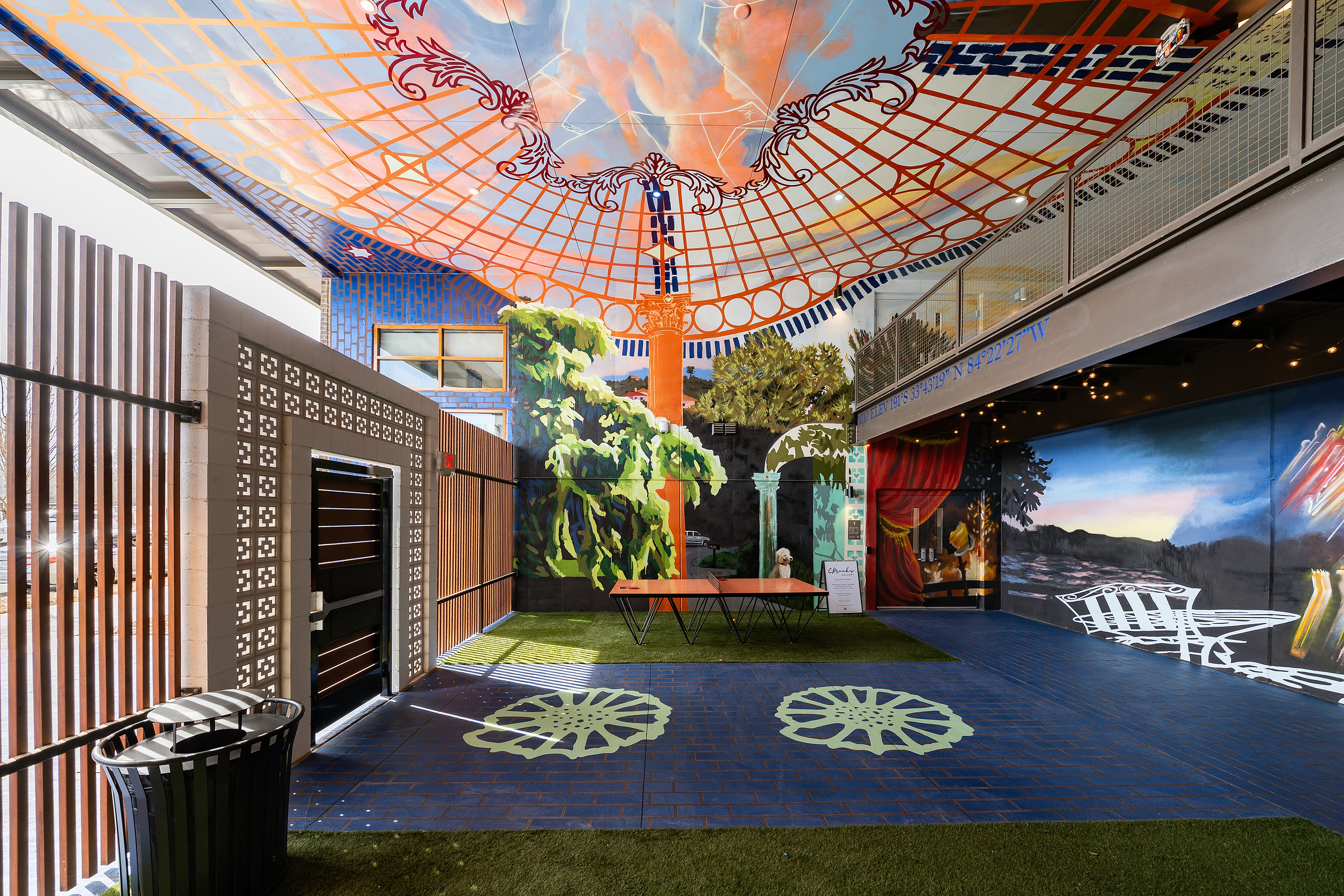 Vibrant communal space with colorful murals, featuring artistic ceiling designs and a blend of open seating, creating a lively and engaging atmosphere.