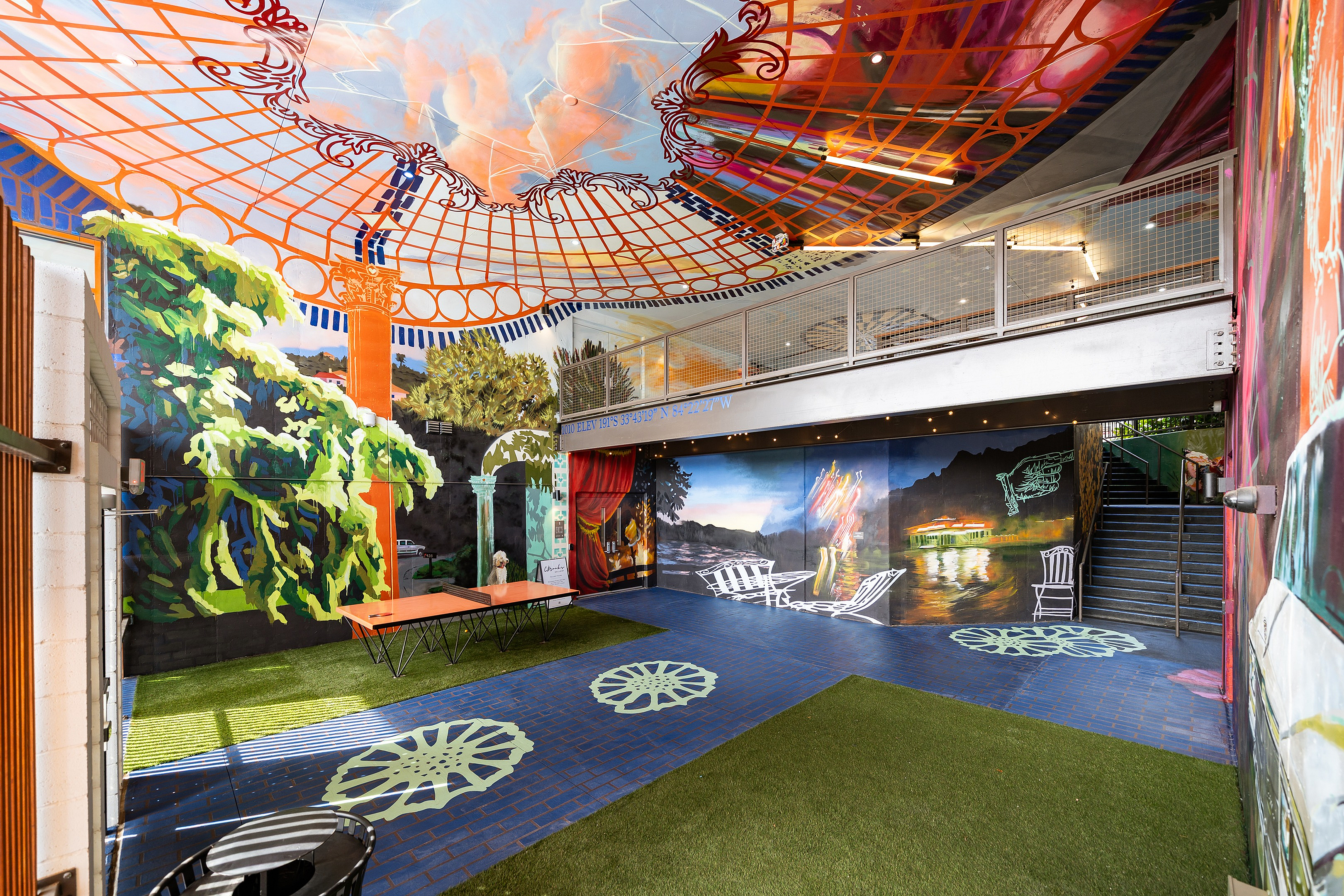 Vibrant indoor space with colorful mural walls, artistic ceiling design, and playful seating area creating a lively atmosphere.