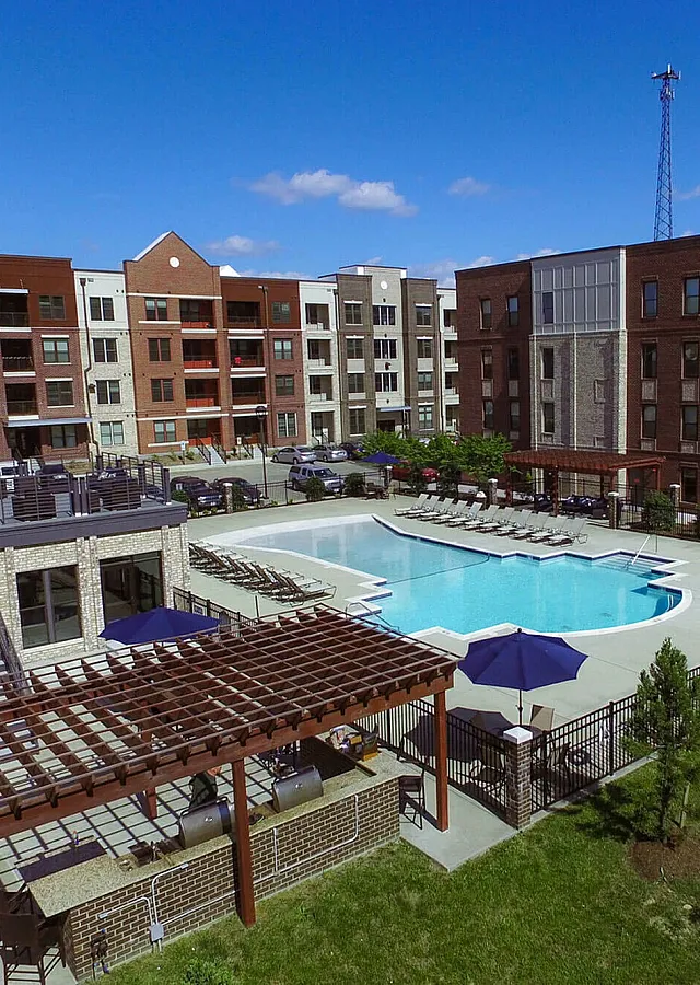 Aerial view of modern apartment complex with spacious pool and lounging area.
