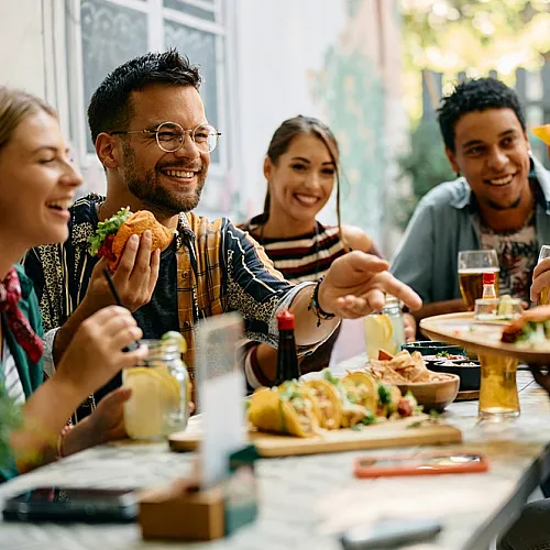 Group of friends enjoying food and drinks at an outdoor cafe