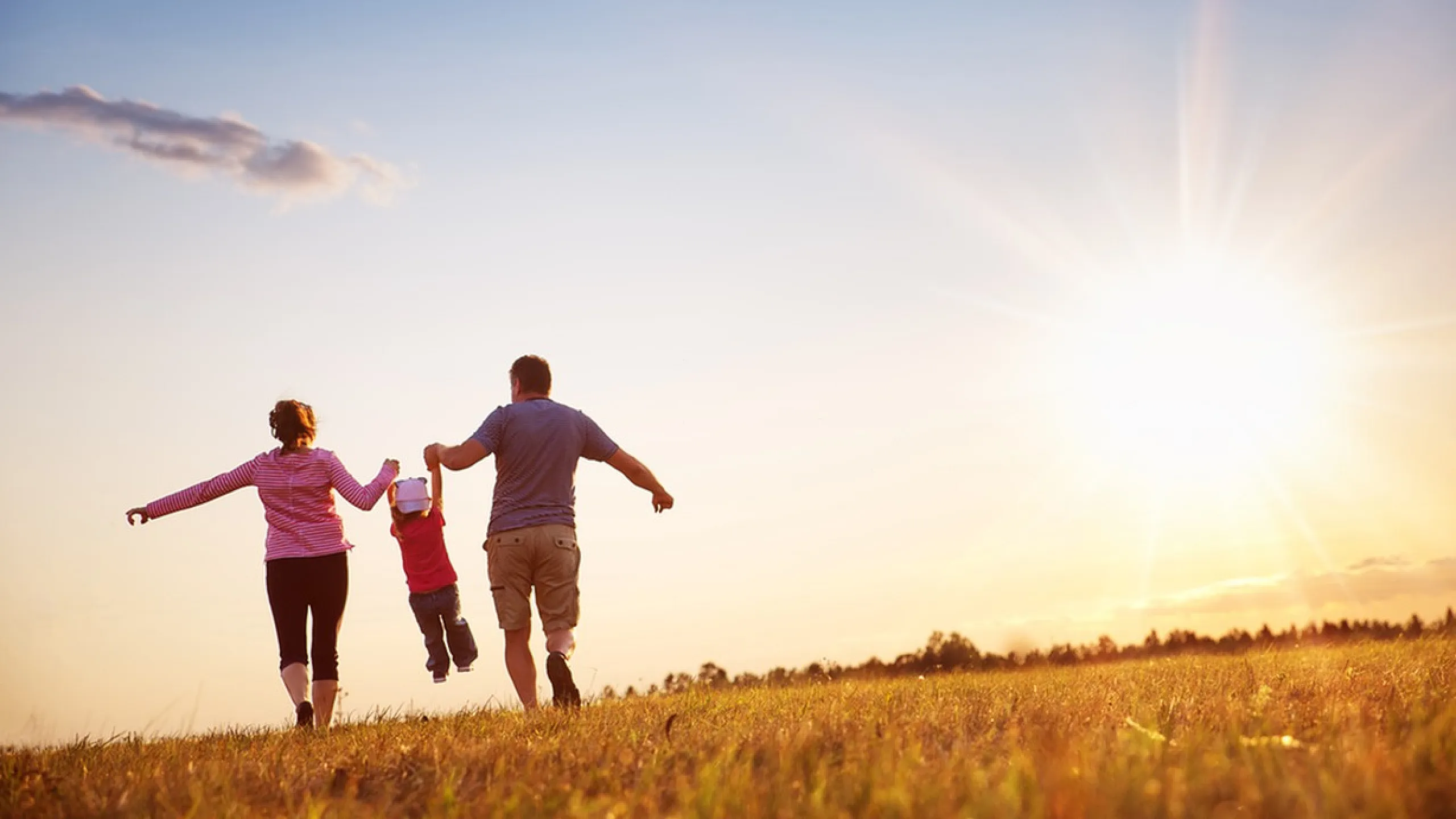 Joyful family playing in open field at sunset