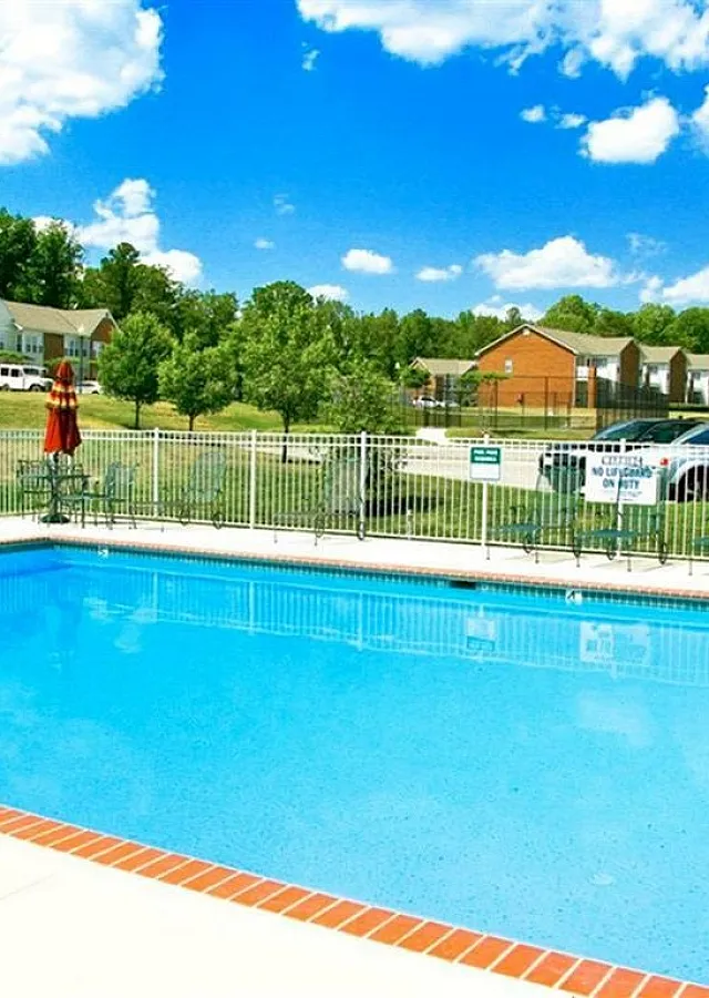 Inviting community pool with crystal clear water, surrounded by lush greenery and modern townhomes.