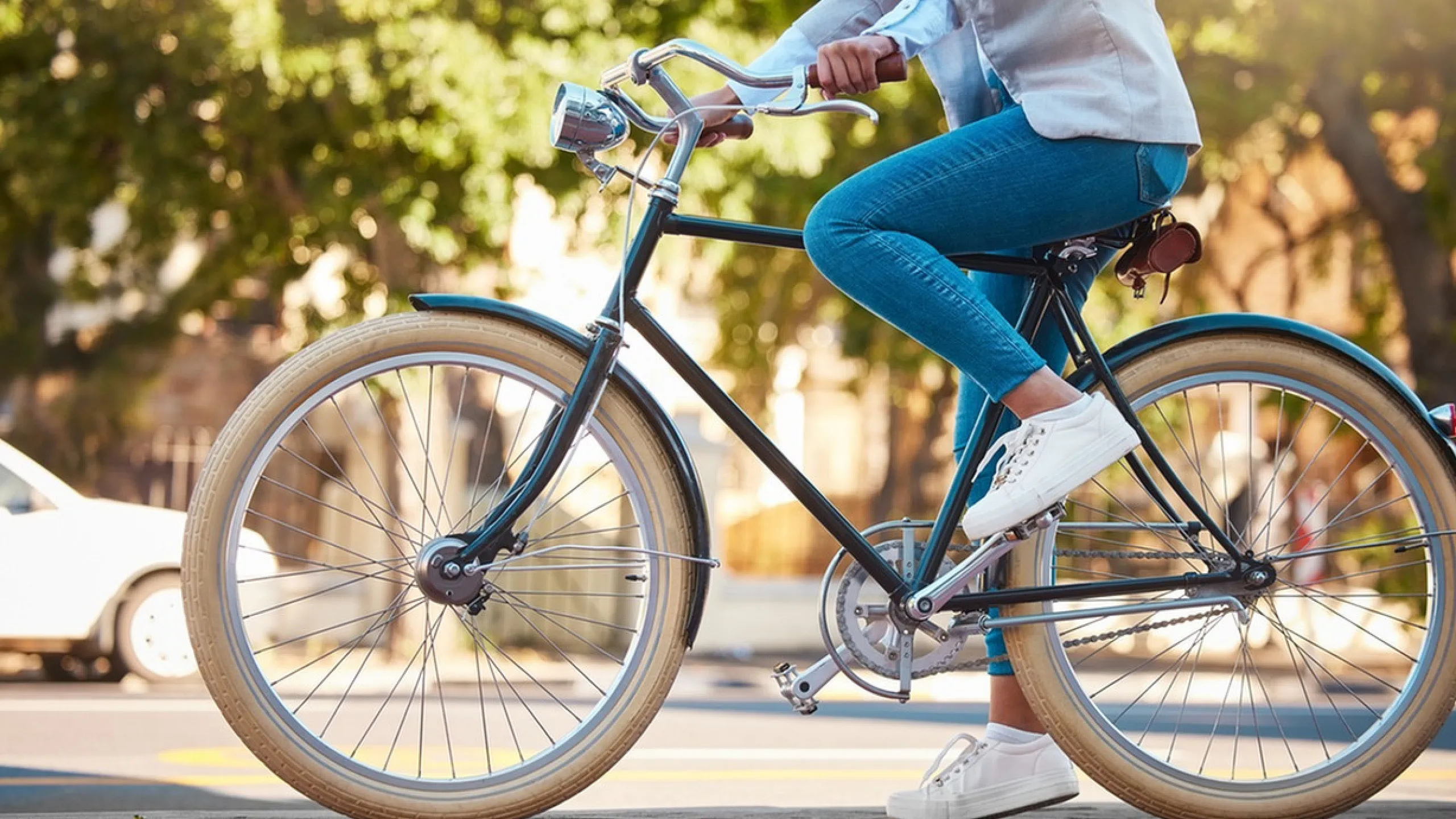 Close-up of a stylish commuter on a vintage bicycle in a sunny urban setting.