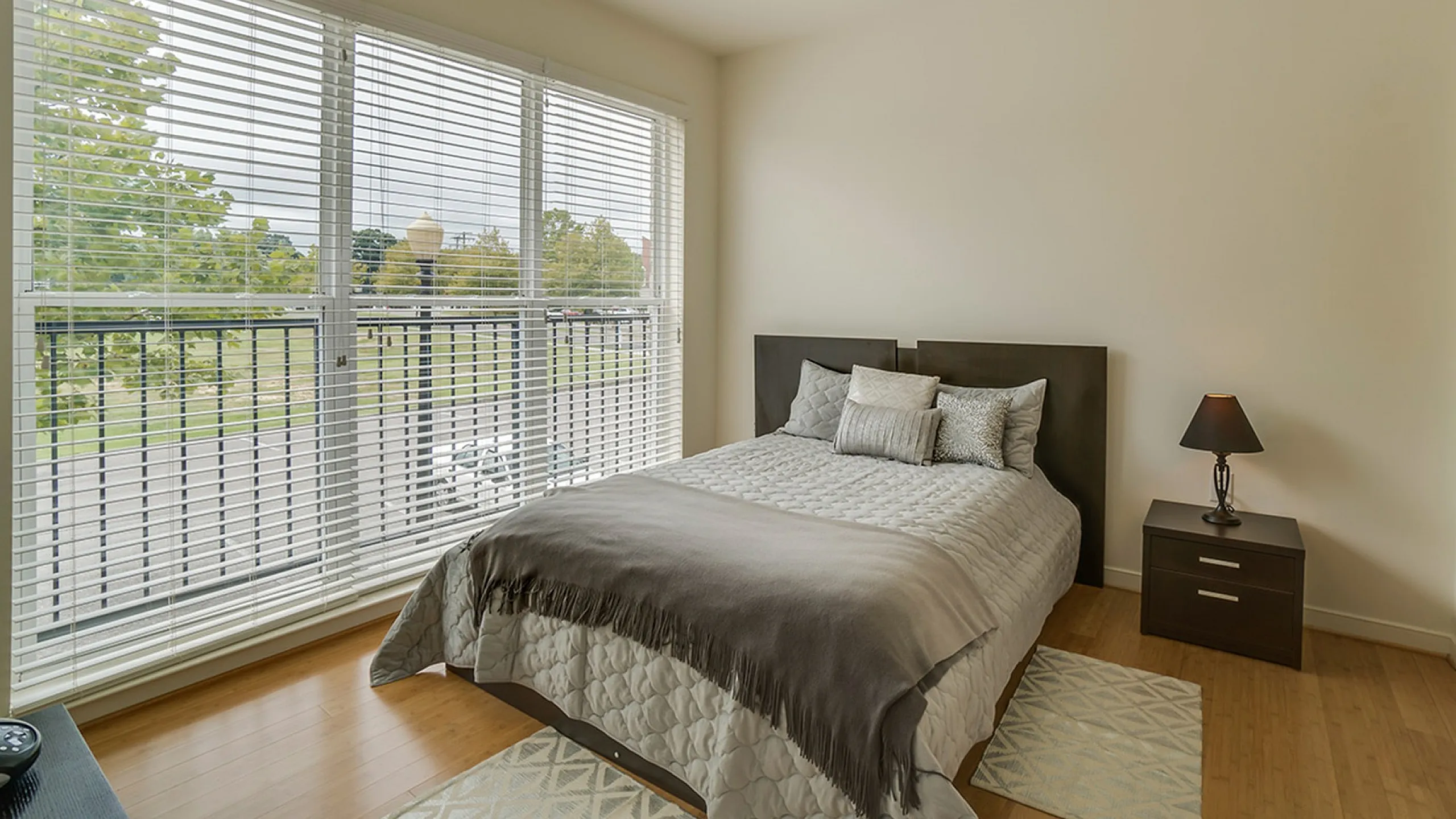 Bright bedroom with a large window, featuring a double bed, soft pillows, and a stylish bedside lamp.