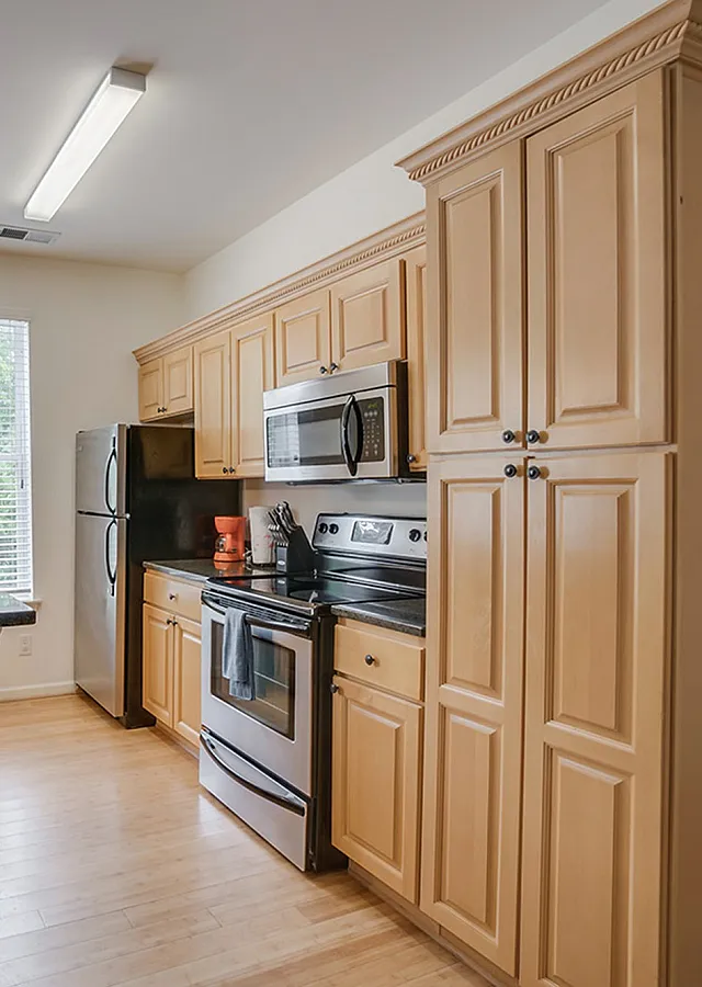 Bright and modern kitchen with wooden cabinetry, stainless steel appliances, and pendant lighting.