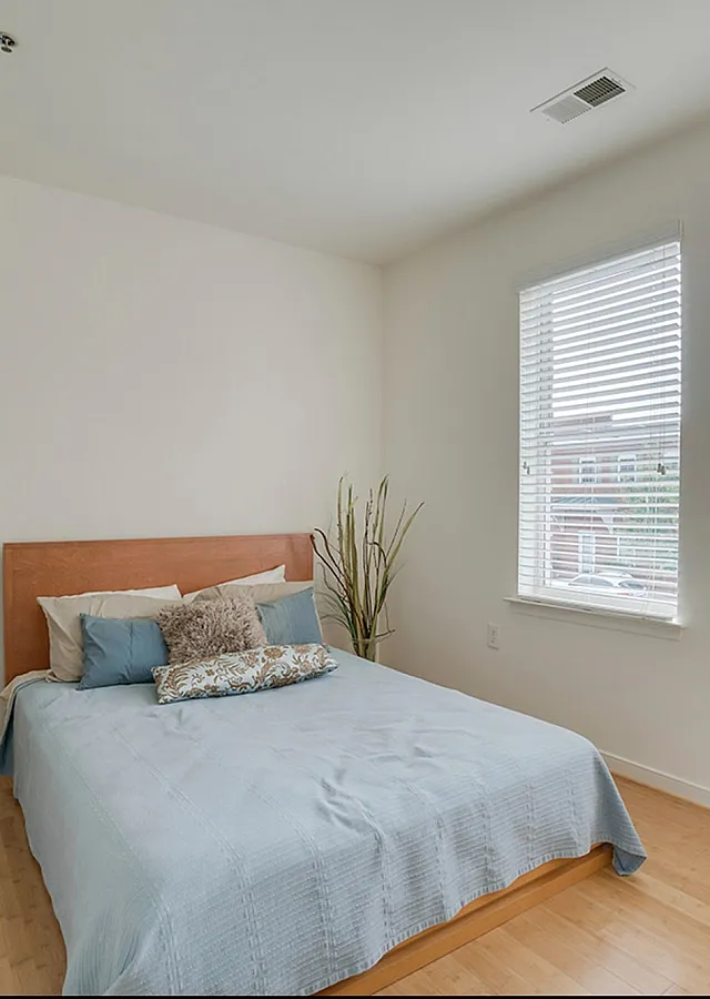 Inviting bedroom with a wooden bed frame, plush pillows, and large windows allowing natural light.