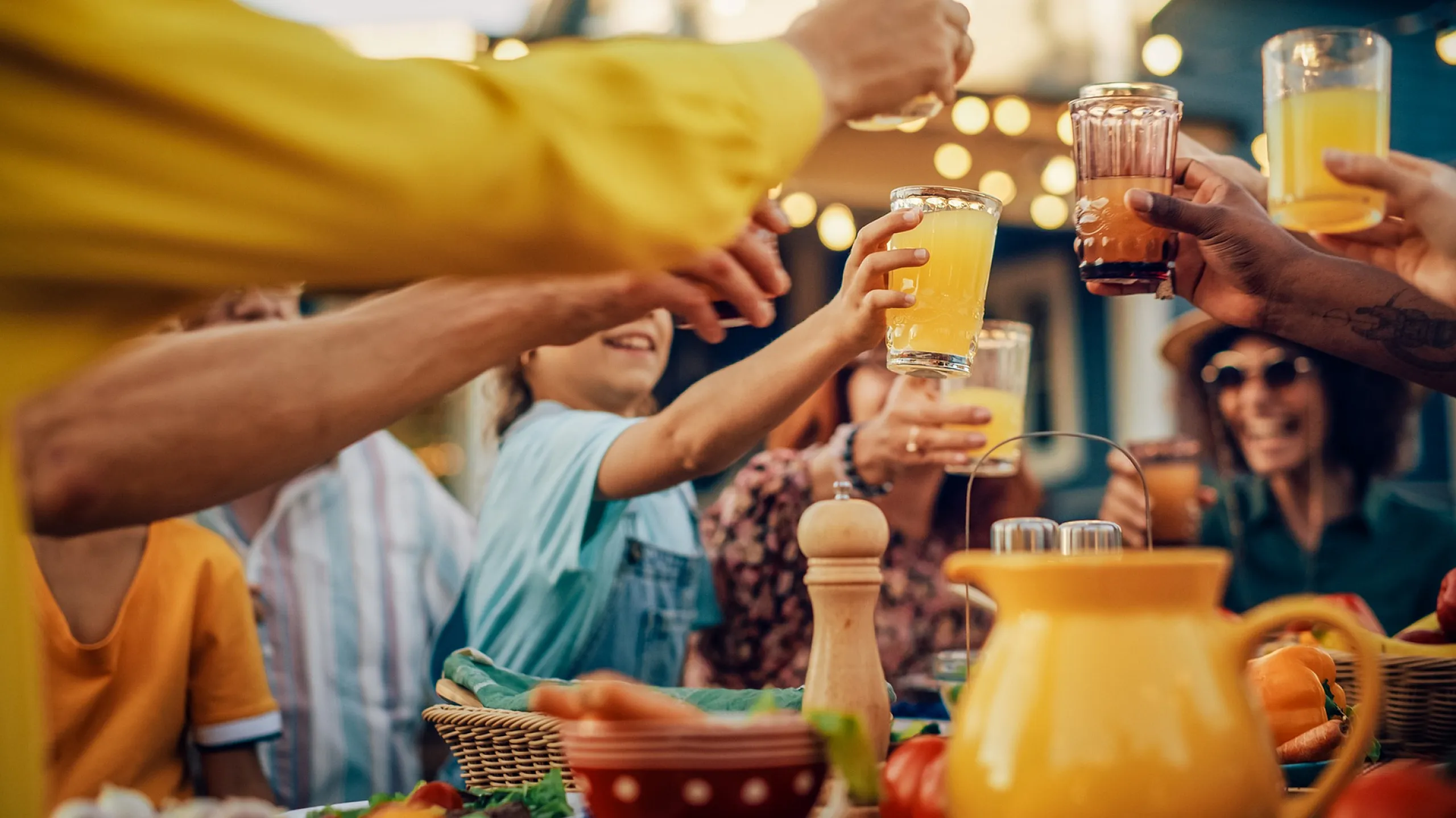 Group of people toasting with glasses of juice at a lively outdoor party.