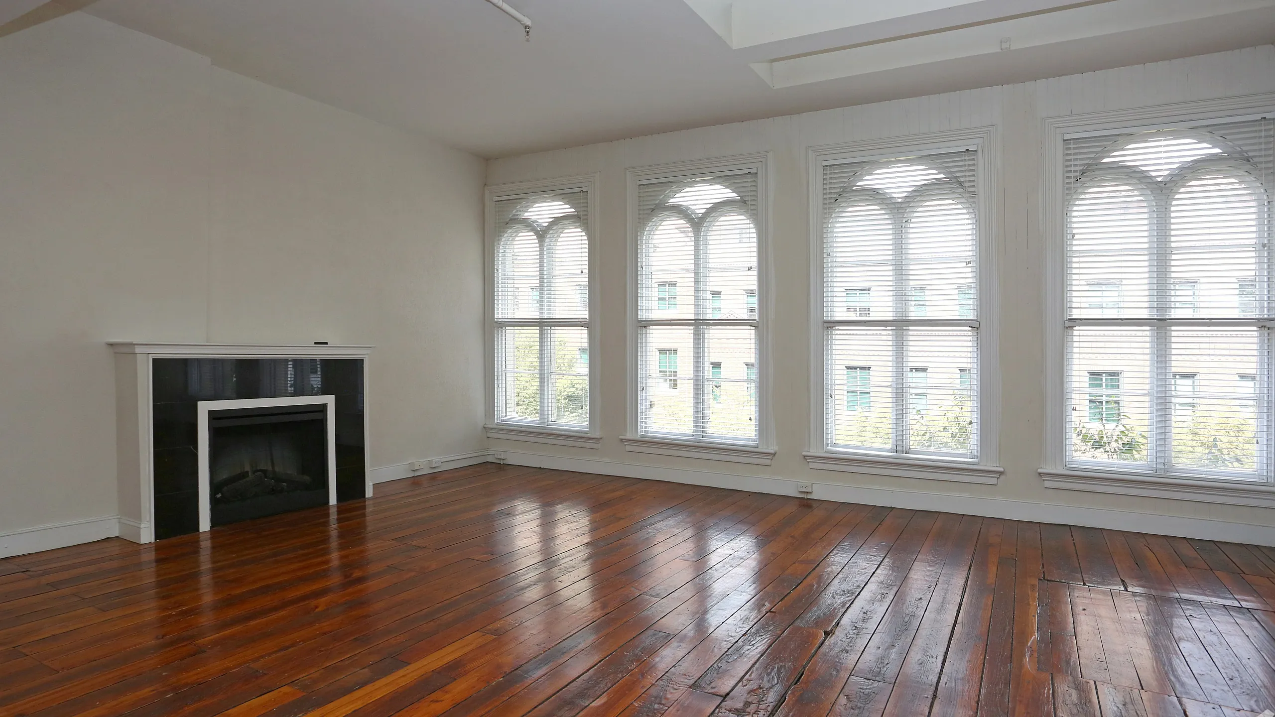Bright and spacious living room featuring hardwood floors, large arch windows, and a modern fireplace.