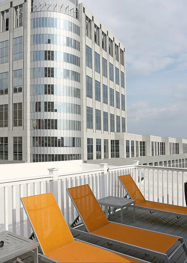Spacious rooftop deck with orange lounge chairs and a cityscape backdrop, ideal for urban relaxation.