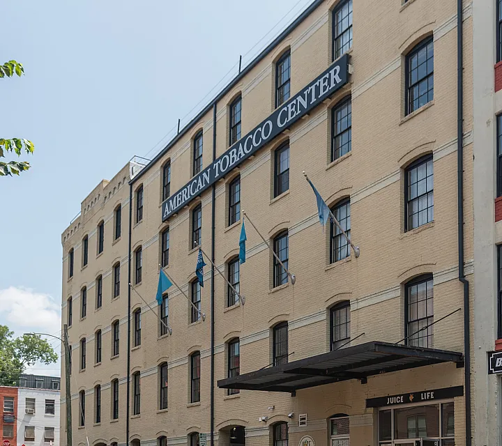Historic brick building with large windows and street-level shops, showcasing urban living potential.