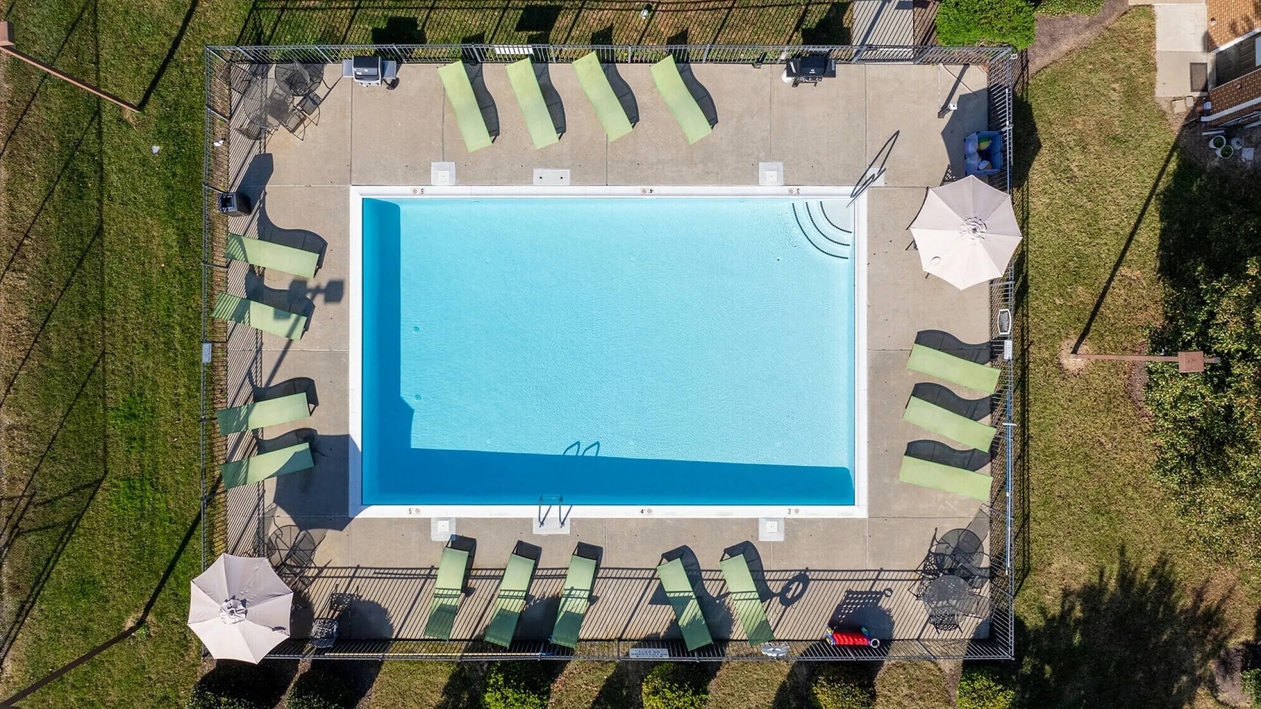 Aerial view of a luxurious outdoor swimming pool with surrounding lounge chairs and umbrellas.