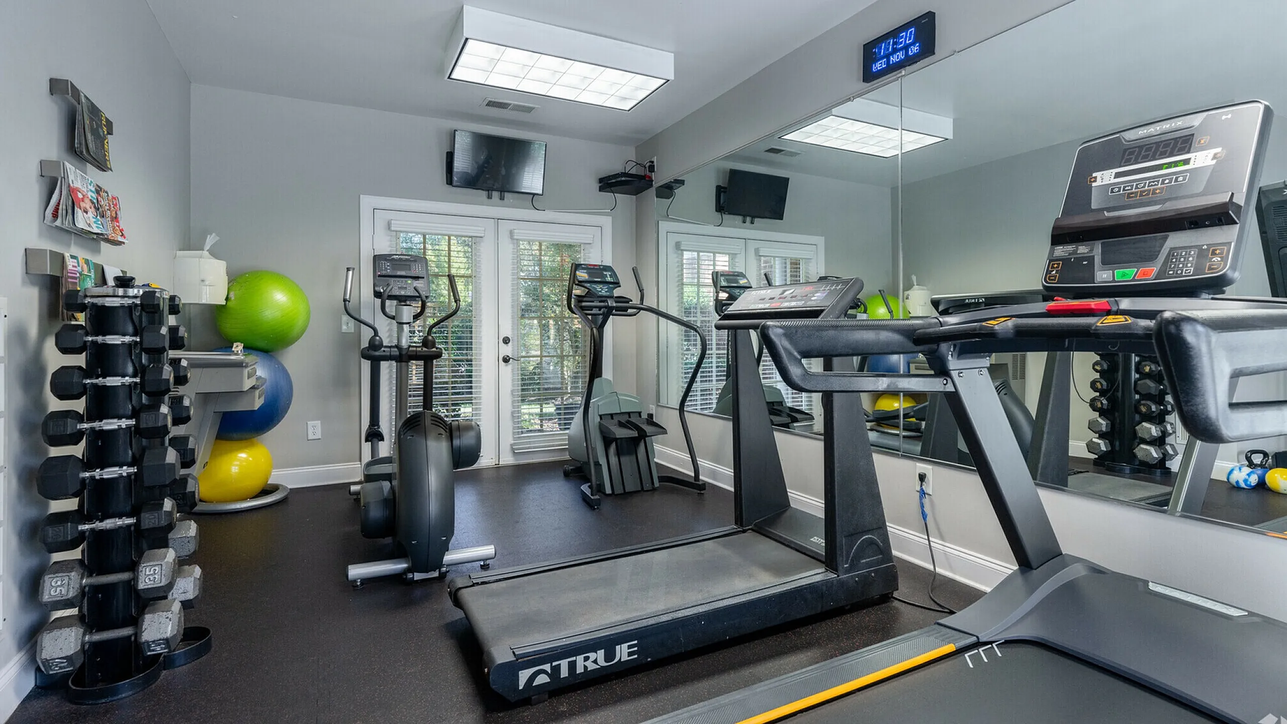 Modern gym with exercise machines, free weights, and fitness balls in a bright, spacious room.