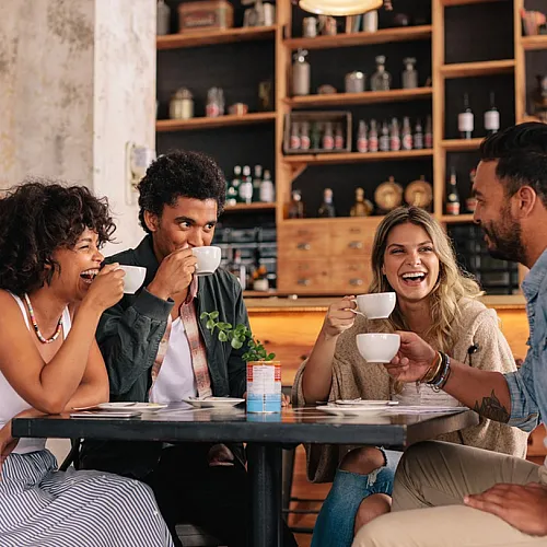 Group of friends enjoying coffee together in a modern café setting.