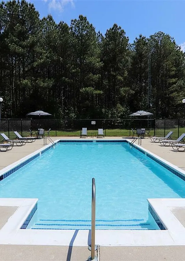 Inviting outdoor pool surrounded by comfortable lounge chairs and lush trees.