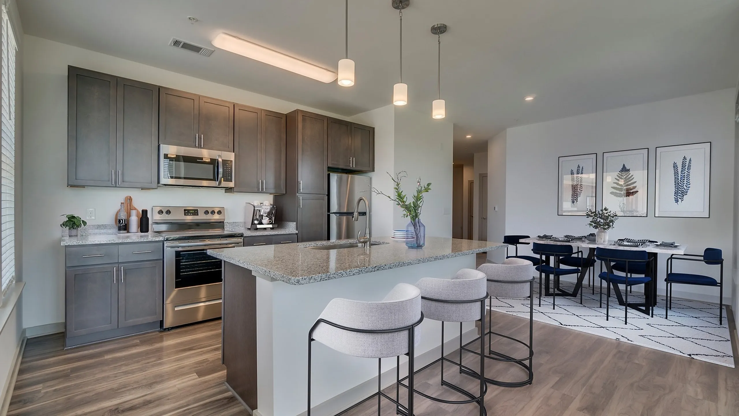Sleek kitchen with a large island and adjacent dining area in a modern apartment setting.