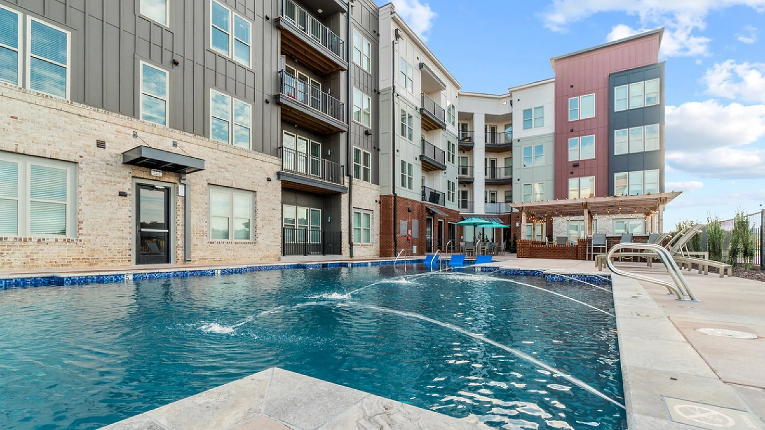 Chic apartment building with a sparkling outdoor swimming pool and stylish lounge area.