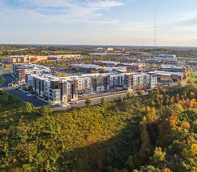 Breathtaking aerial view of modern apartment complex surrounded by lush greenery and vibrant autumn foliage.
