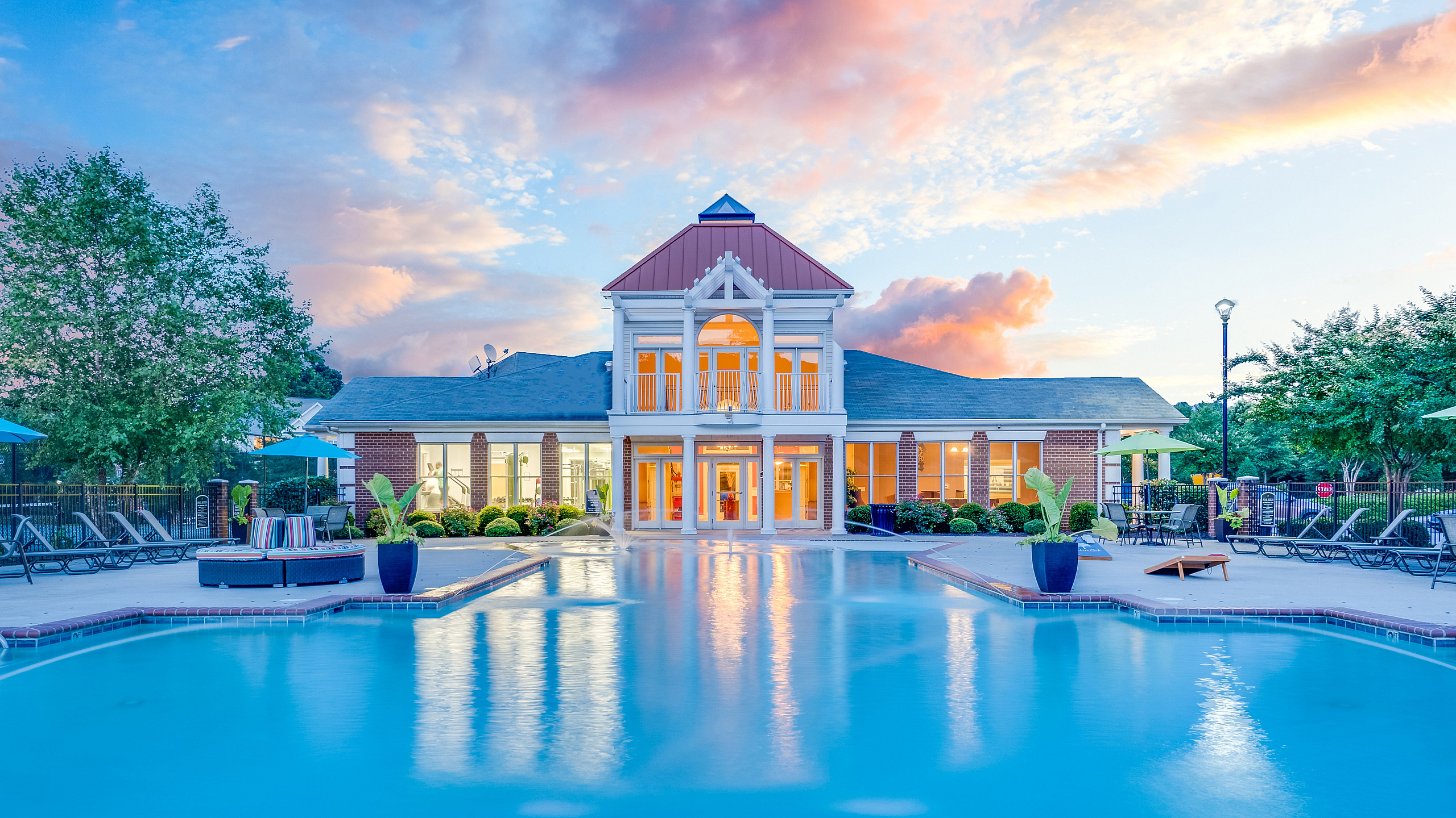 Elegant residential pool area with modern architecture and vibrant sunset backdrop.