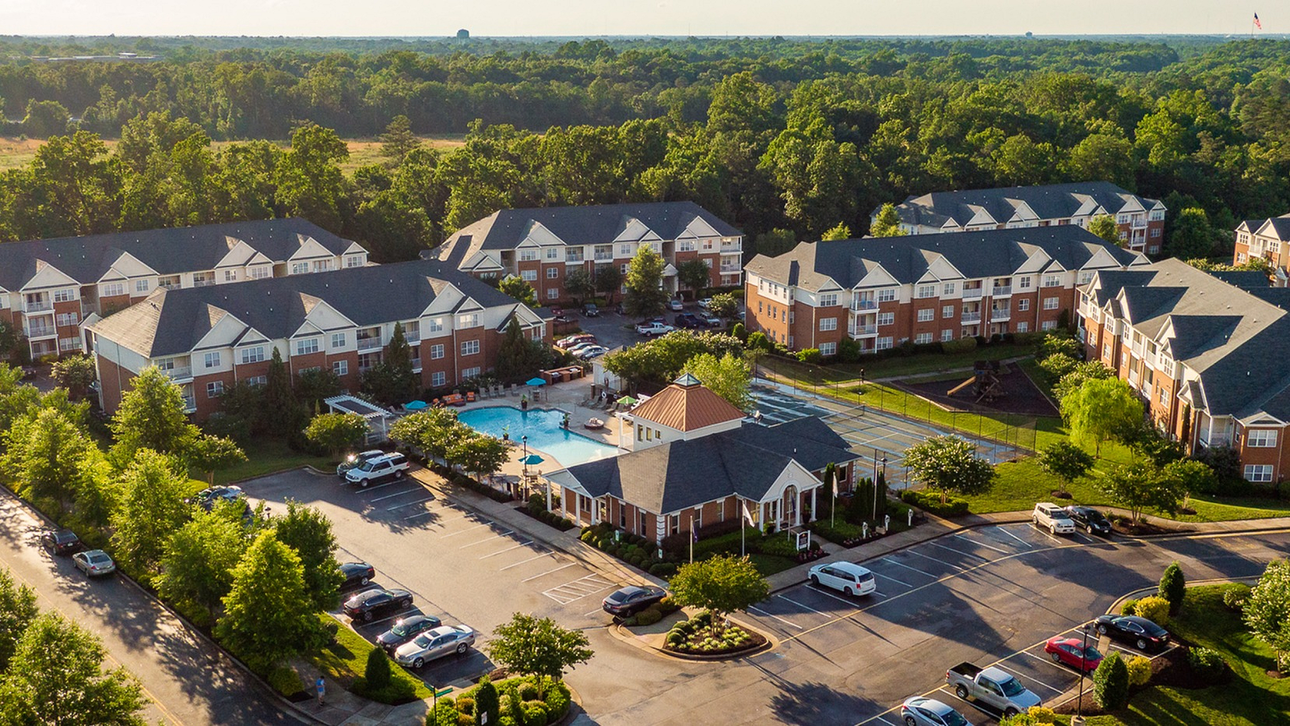 Aerial view of a charming apartment complex with lush greenery and a central pool area.