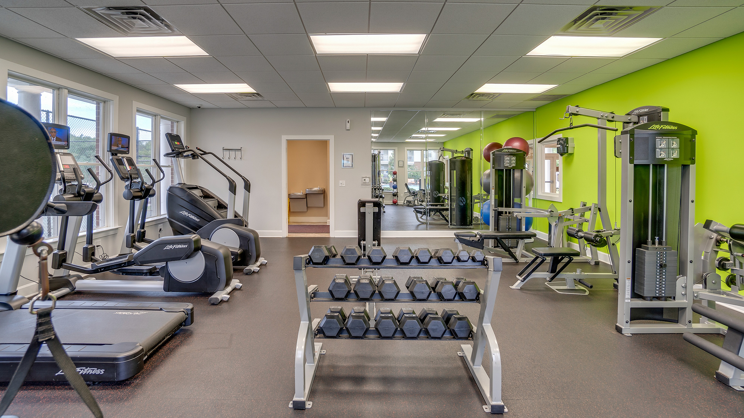 Modern fitness center with various exercise equipment including treadmills, stationary bikes, and weight machines.