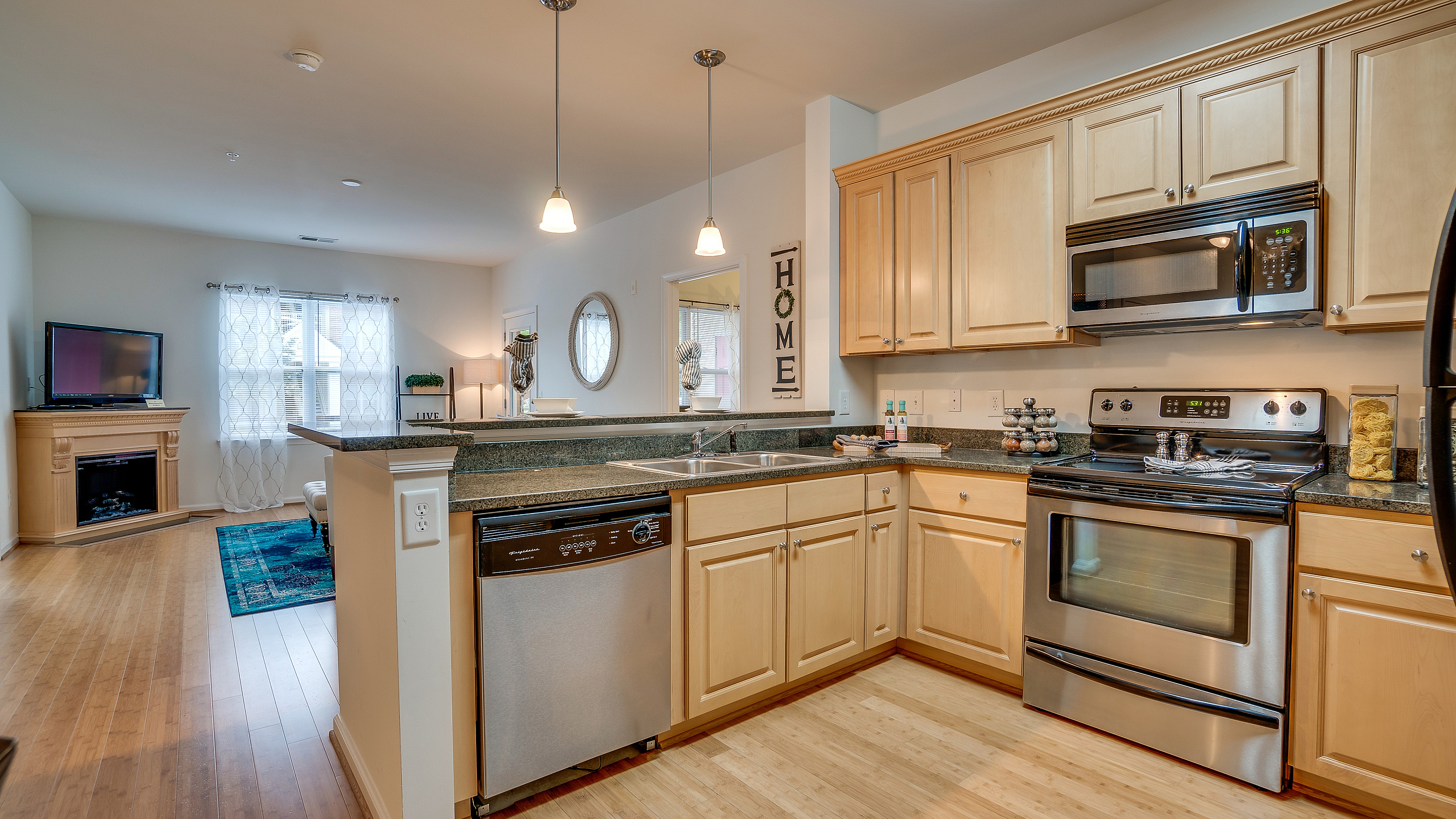 Inviting kitchen with light wood cabinets, stainless steel appliances, and open view of a cozy living area.
