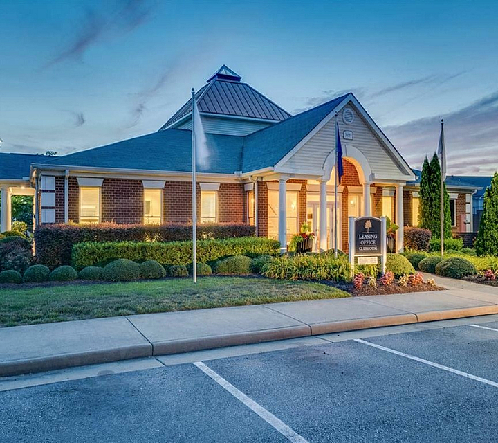 Inviting leasing office with warm lighting at twilight, surrounded by lush landscaping.