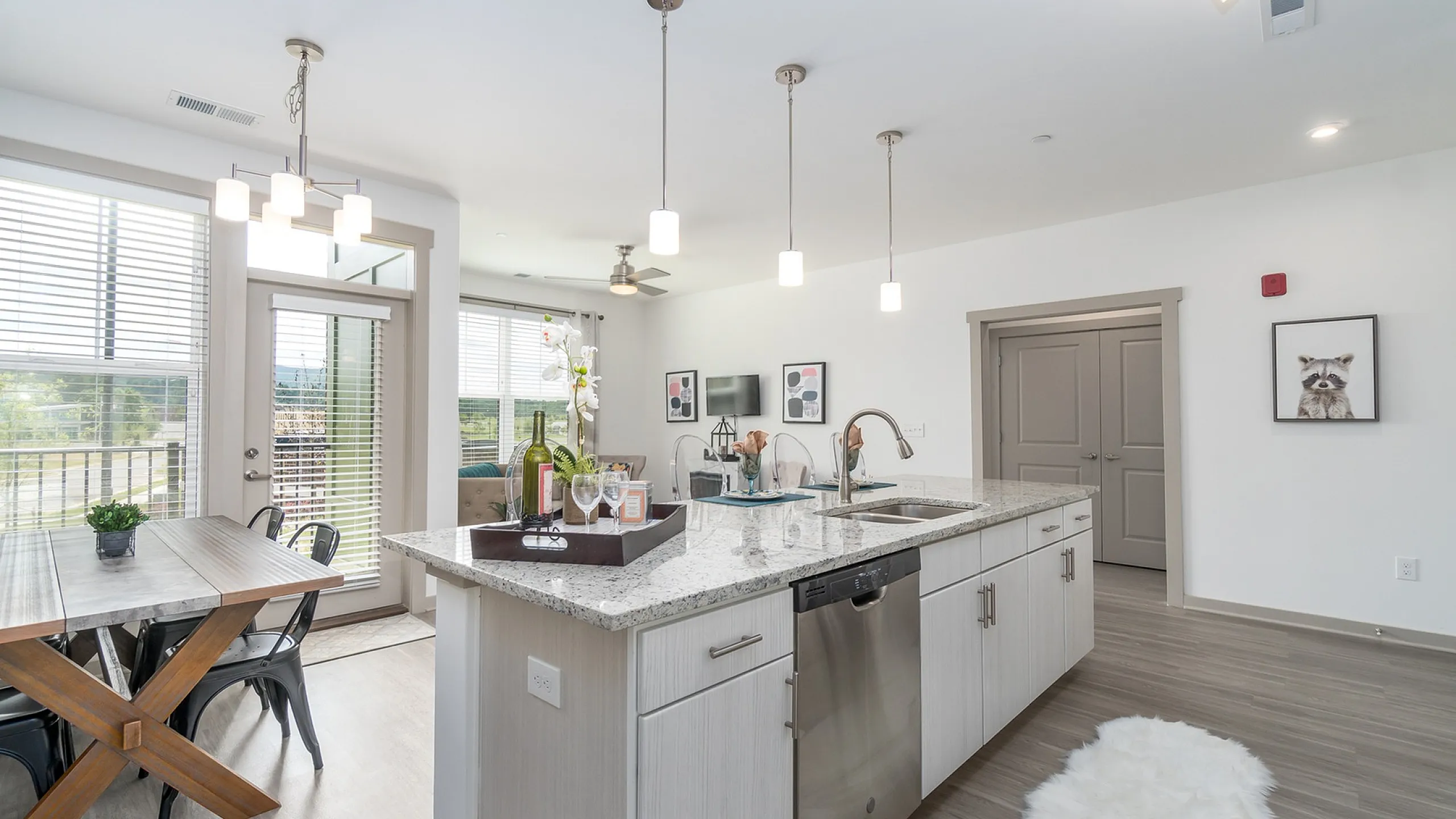 Bright, modern kitchen with granite countertops and dining area featuring a rustic wooden table.