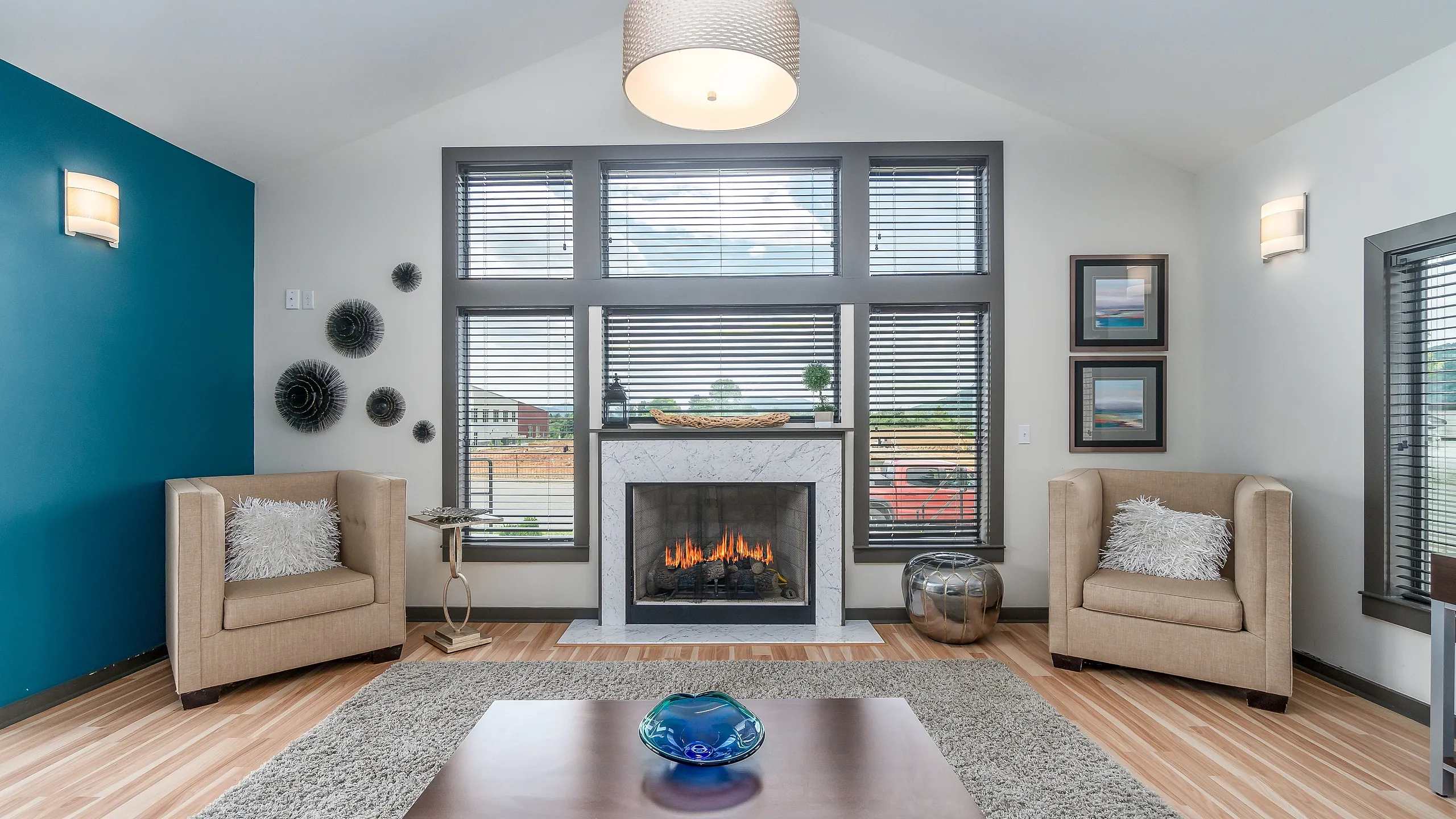 Modern living room with stylish decor, featuring a cozy fireplace, plush armchairs, and large windows offering abundant natural light.