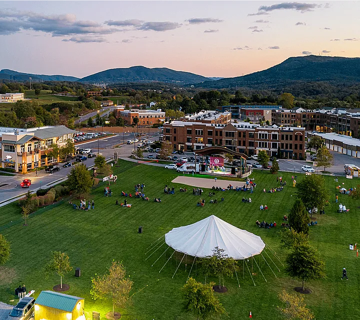 Aerial view of a lively community with a central park and surrounding modern buildings at dusk.