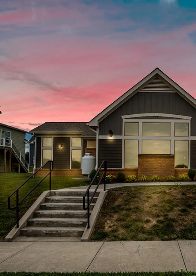 Exterior view of a charming house with a beautiful sunset sky, featuring modern architecture and landscaped front yard.