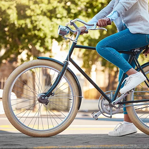 Close-up of a person riding a stylish bicycle in a sunny urban setting.