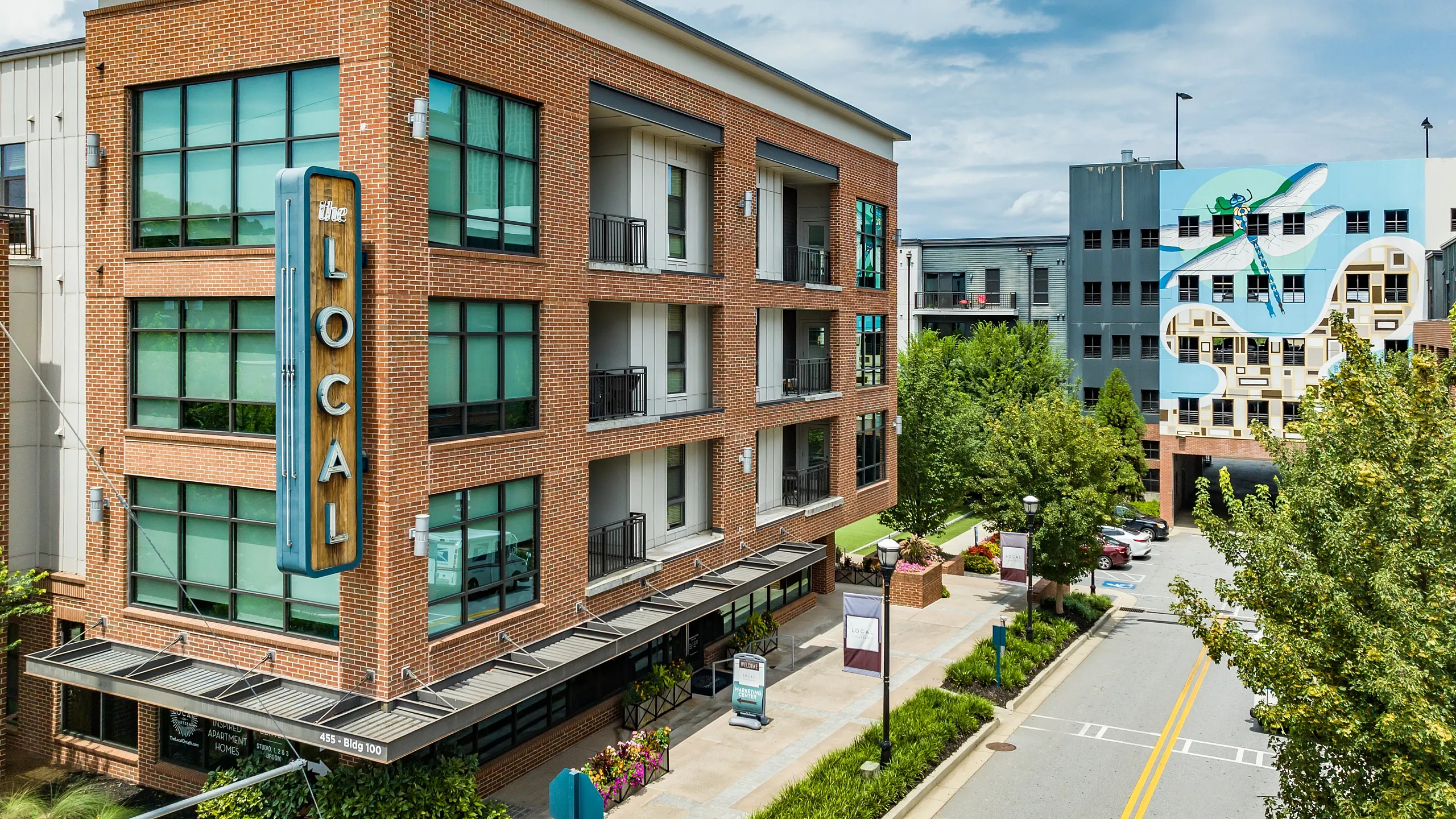 Brick facade of a modern apartment building featuring large windows and a prominent 'Local' sign.