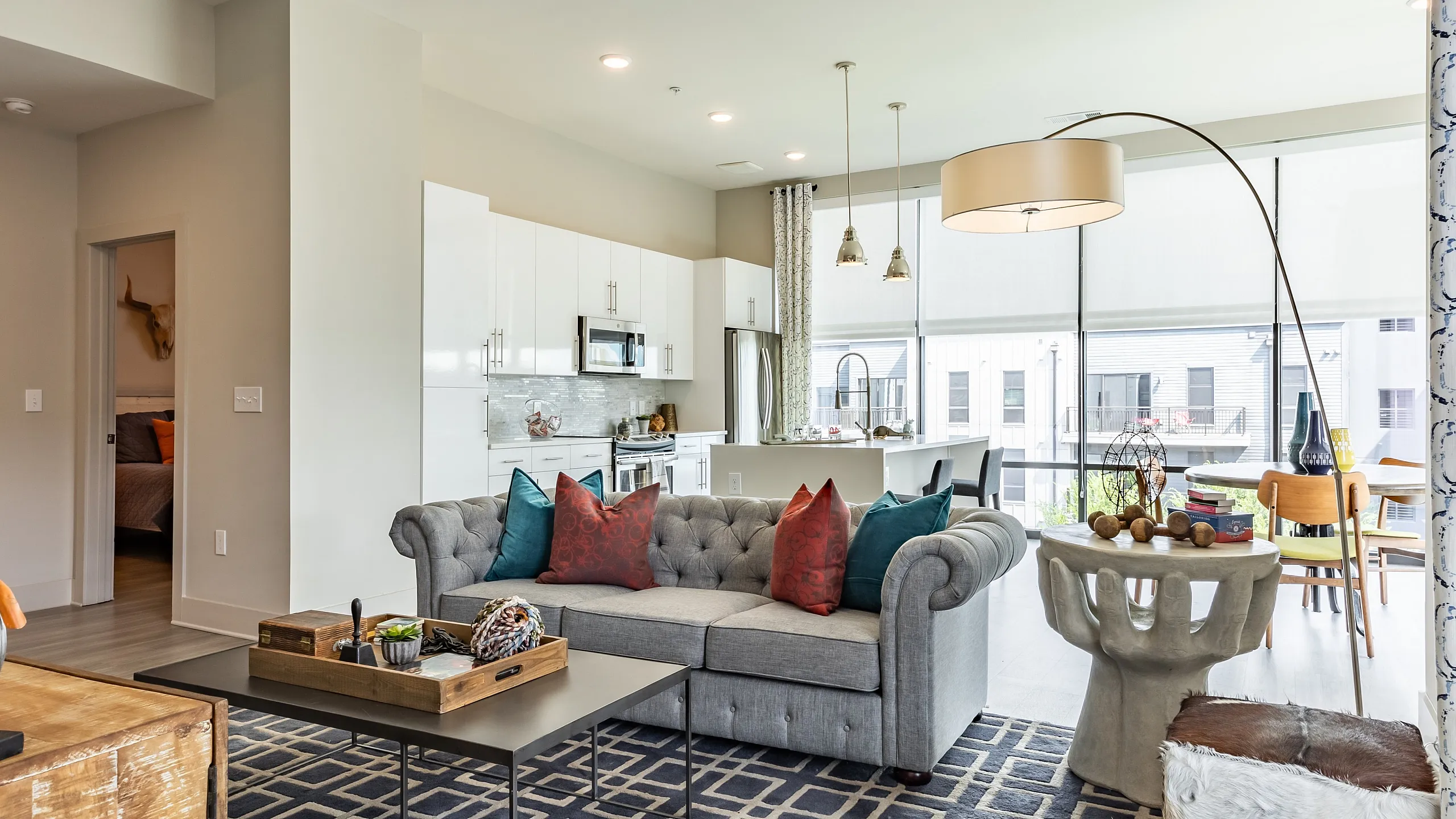Sophisticated apartment interior featuring a cozy living area with a plush gray sofa, colorful cushions, and a stylish open-concept kitchen.