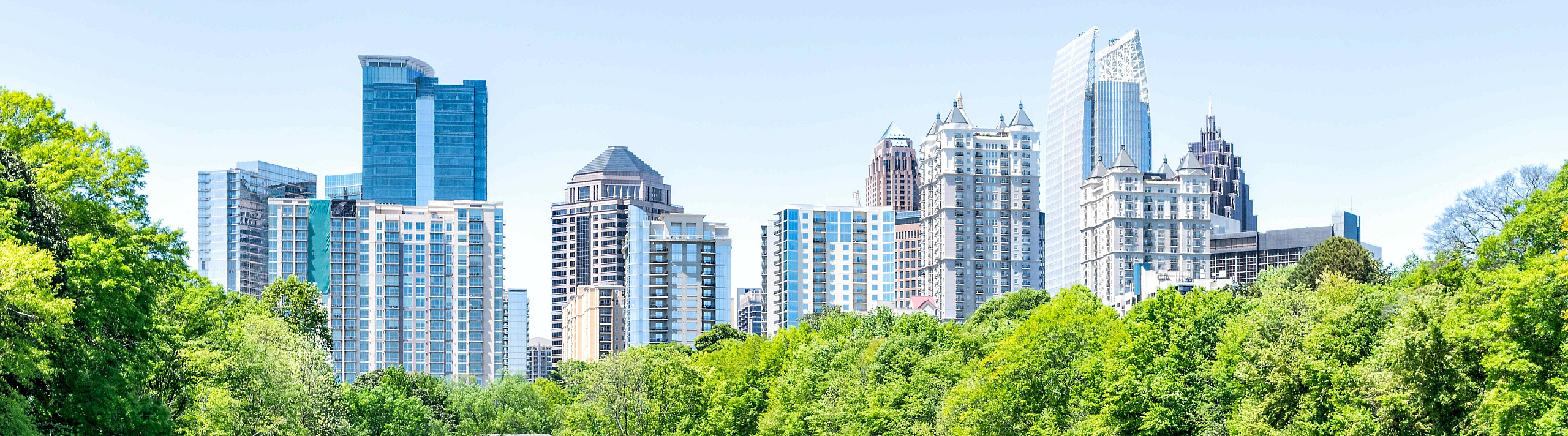 Scenic city skyline view with a tranquil lake surrounded by lush greenery.