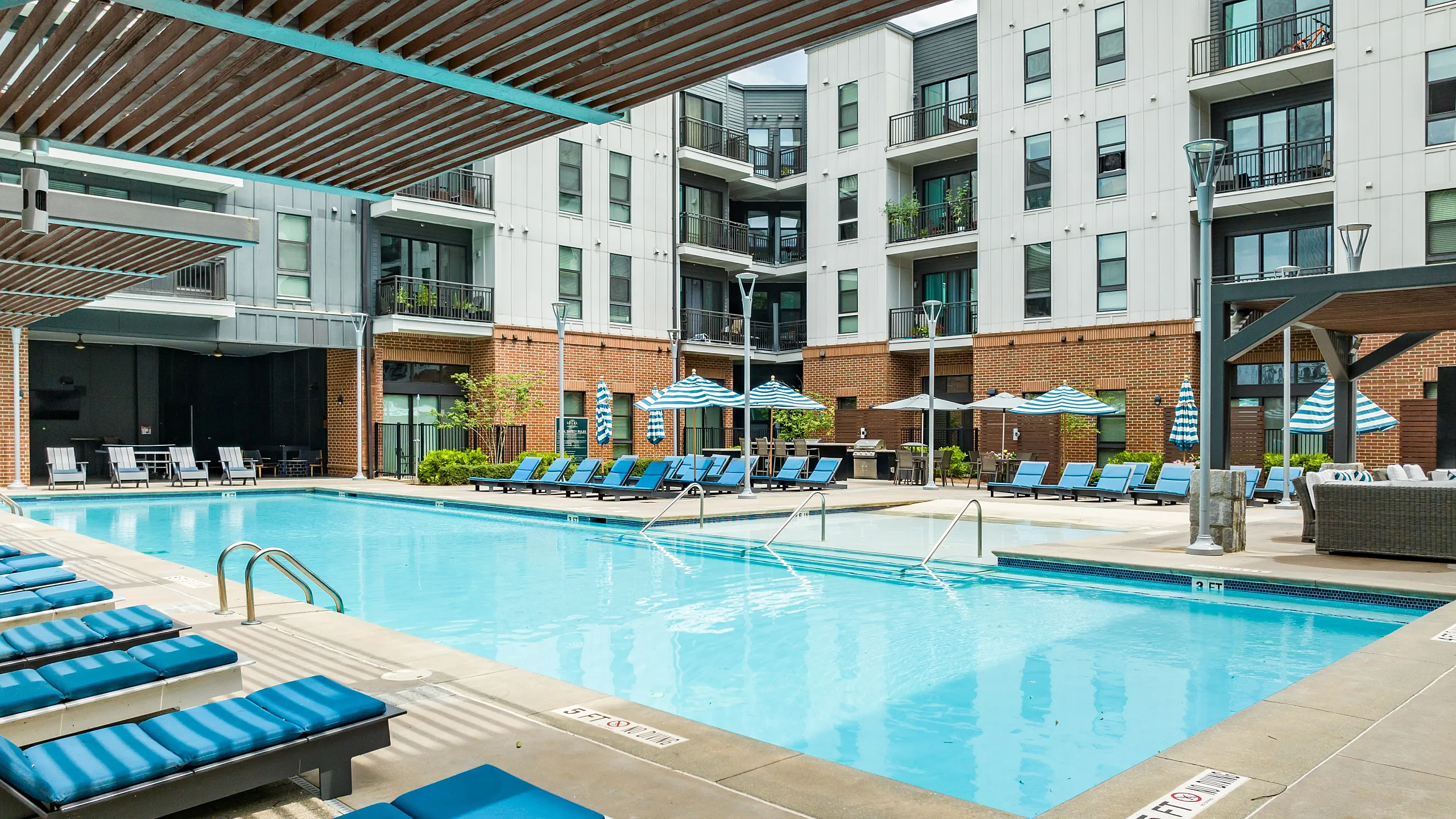 Elegant outdoor pool surrounded by stylish loungers and modern apartment buildings.