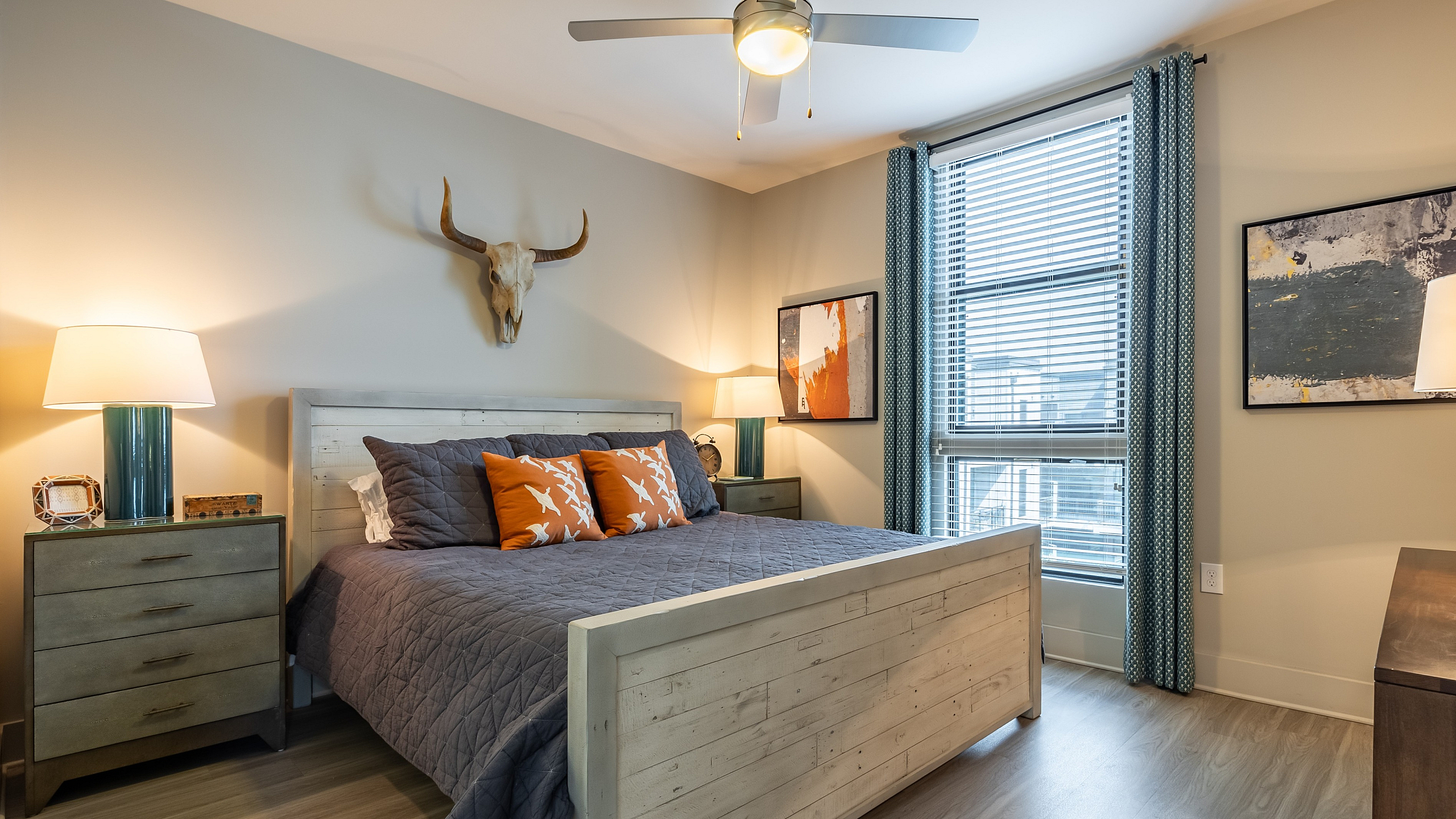 Stylish bedroom with modern decor, featuring a cozy bed, artistic wall hangings, and a large window with natural light.